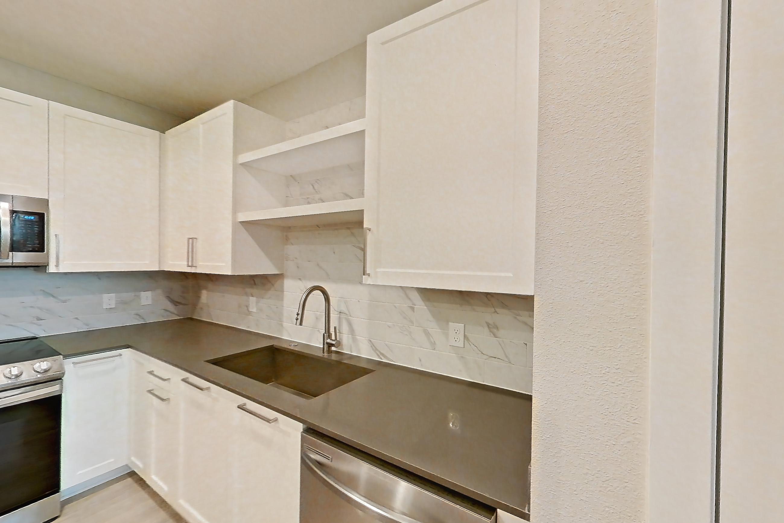 Kitchen with dark countertops, dishwasher, electric range, light wood-finish flooring, microwave, oven/range, and stainless steel appliances, Apartment 2114 at Cortland Nona