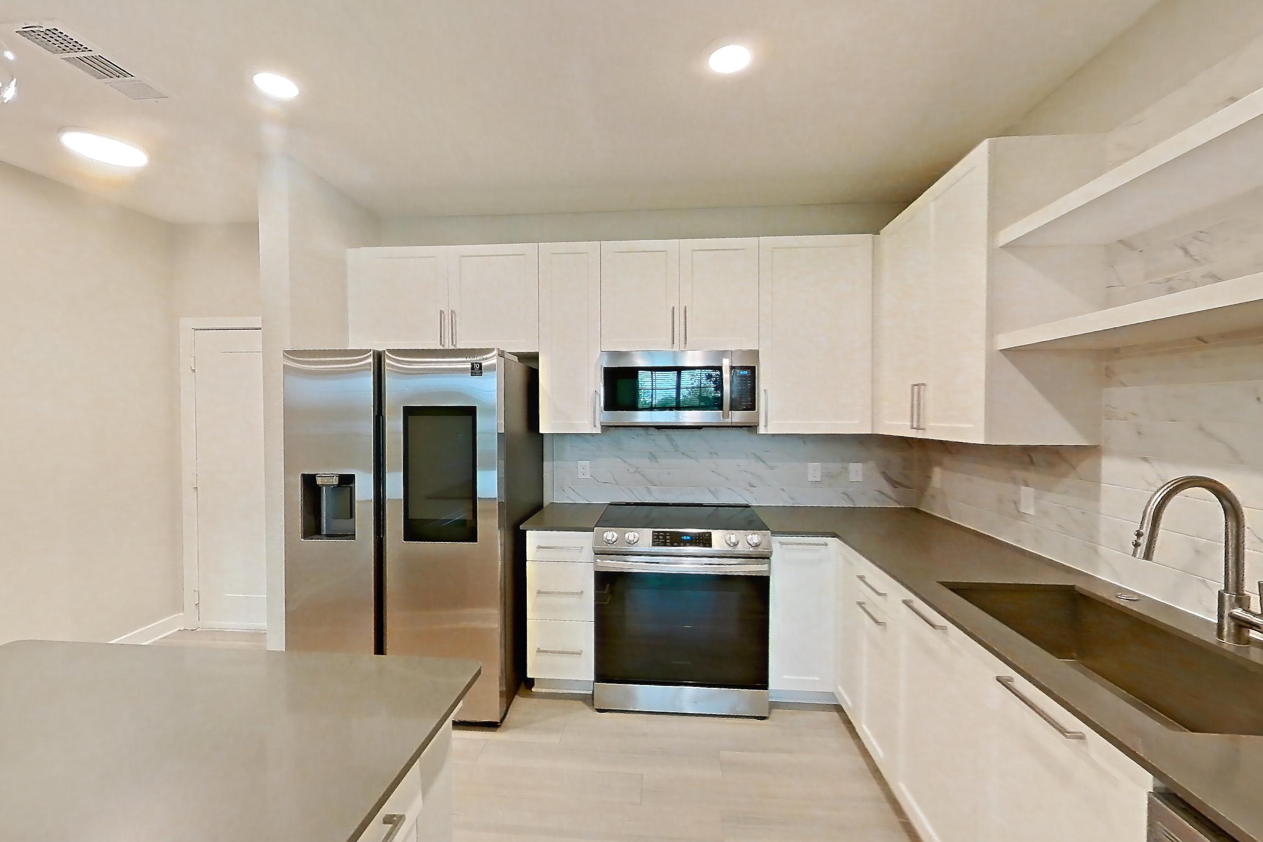 Kitchen with dark countertops, dishwasher, electric range, light wood-finish flooring, microwave, oven/range, and stainless steel appliances, Apartment 2114 at Cortland Nona