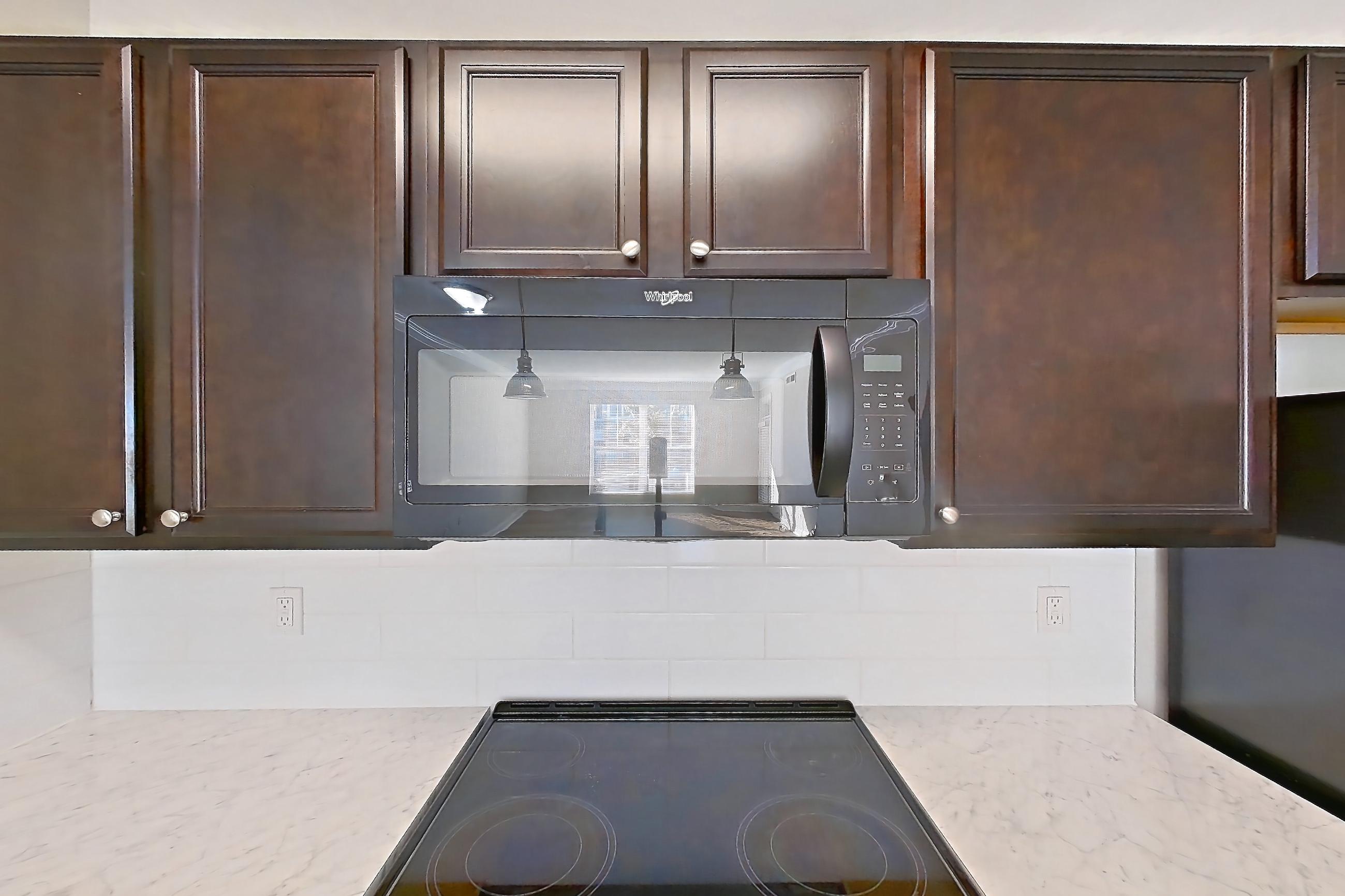Kitchen with black appliances, electric range, light countertops, light wood-finish flooring, oven/range, and refrigerator, Apartment M265 at Cortland Northlake
