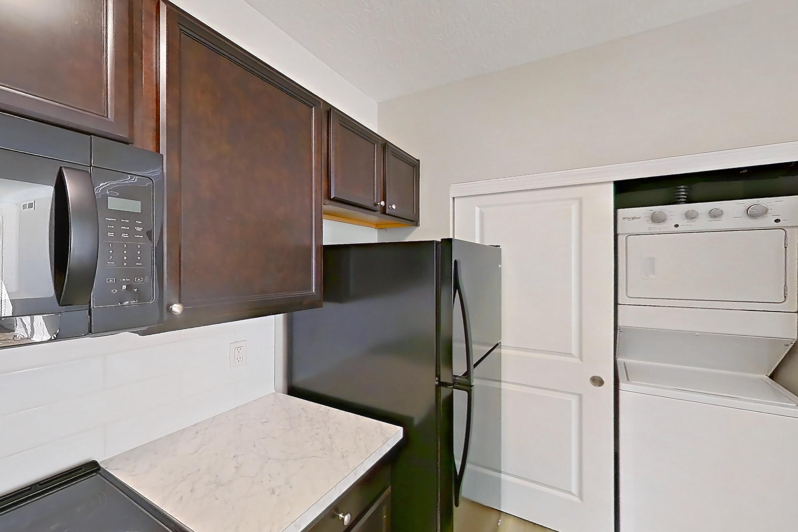 Kitchen with black appliances, electric range, light countertops, light wood-finish flooring, oven/range, and refrigerator, Apartment M265 at Cortland Northlake