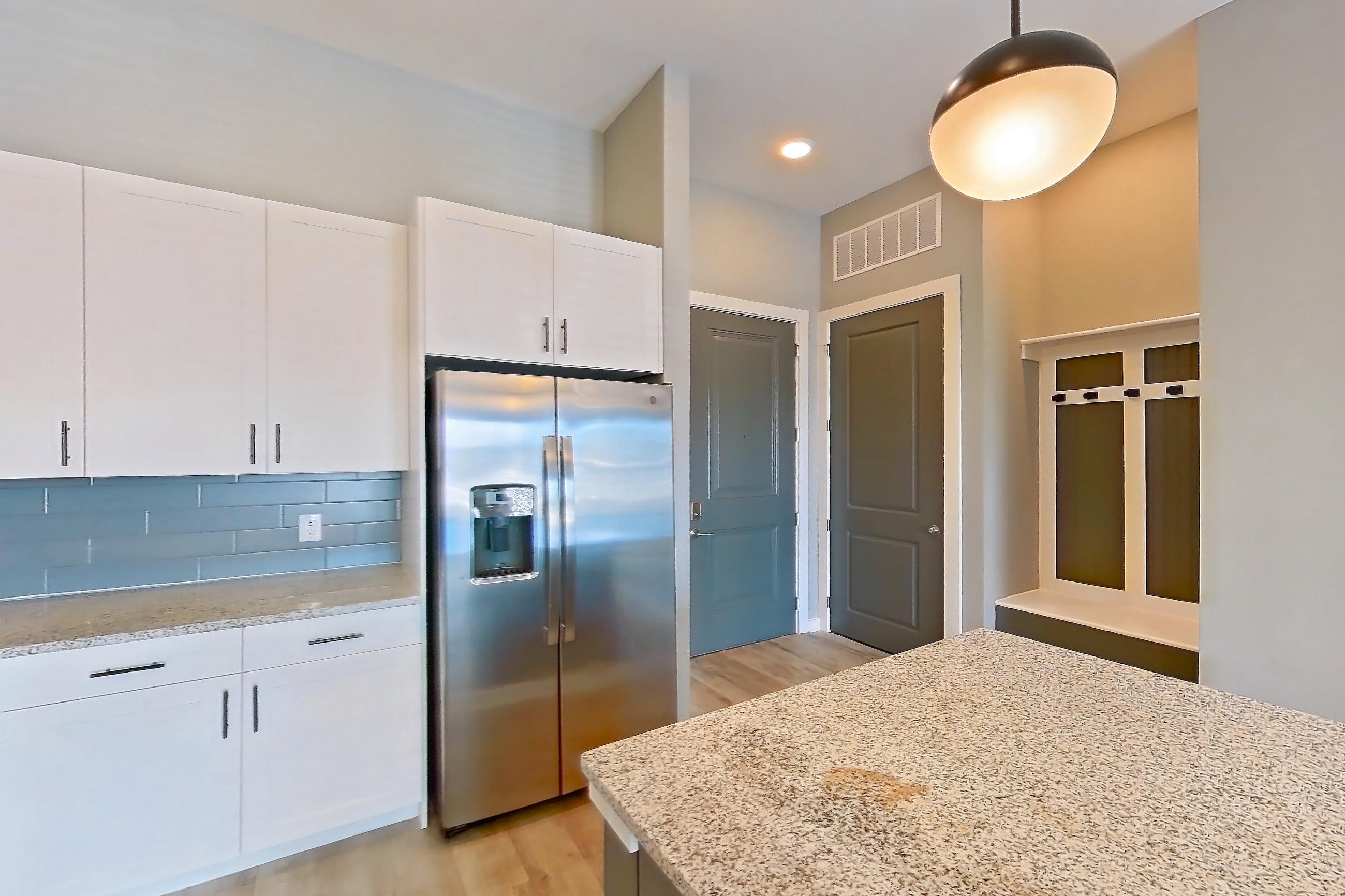 Kitchen with dishwasher, electric range, light countertops, light stone countertops, light wood-finish flooring, microwave, oven/range, refrigerator, stainless steel appliances, and water & ice dispenser, Apartment 2-135 at Cortland Cary