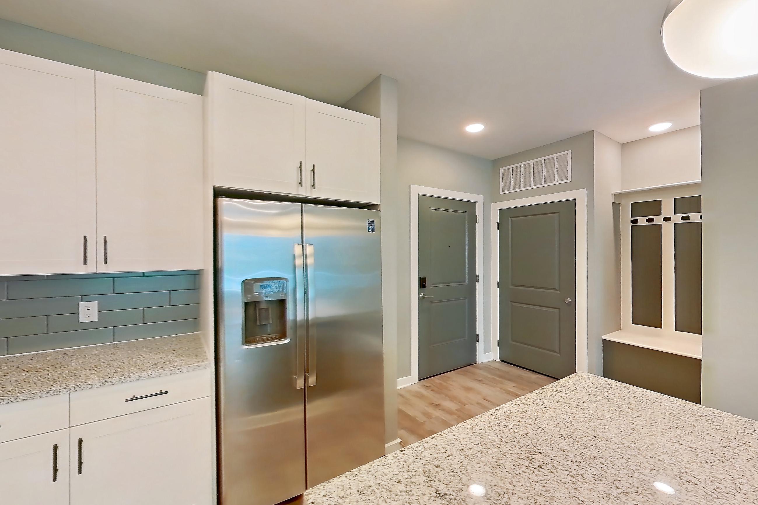 Kitchen with dishwasher, electric range, light countertops, light stone countertops, light wood-finish flooring, microwave, oven/range, refrigerator, stainless steel appliances, and water & ice dispenser, Apartment 1-122 at Cortland Cary