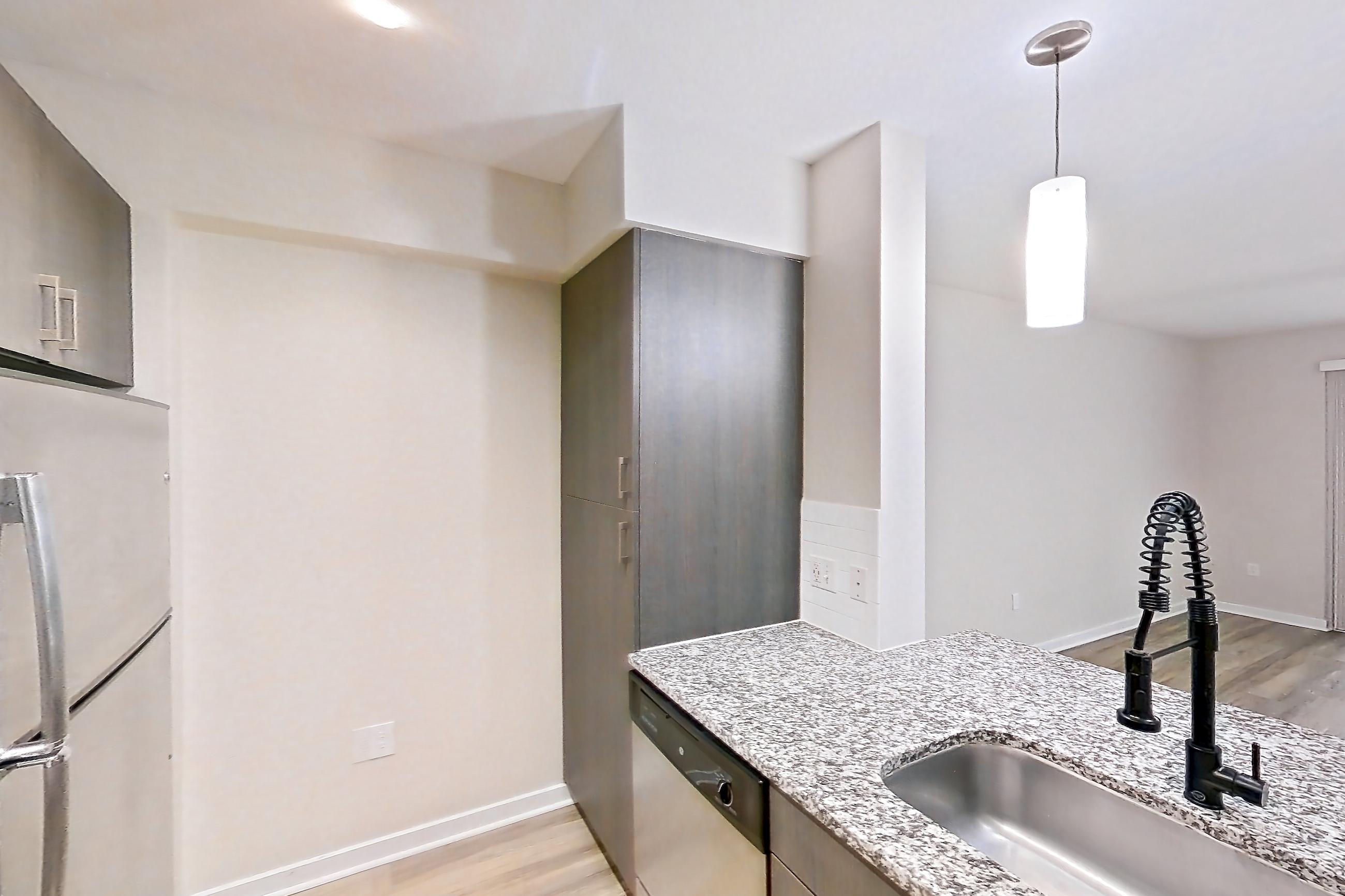Kitchen with dishwasher, electric range, kitchen island, light stone countertops, light wood-finish flooring, oven/range, refrigerator, and stainless steel appliances, Apartment 01104 at Cortland Hollywood