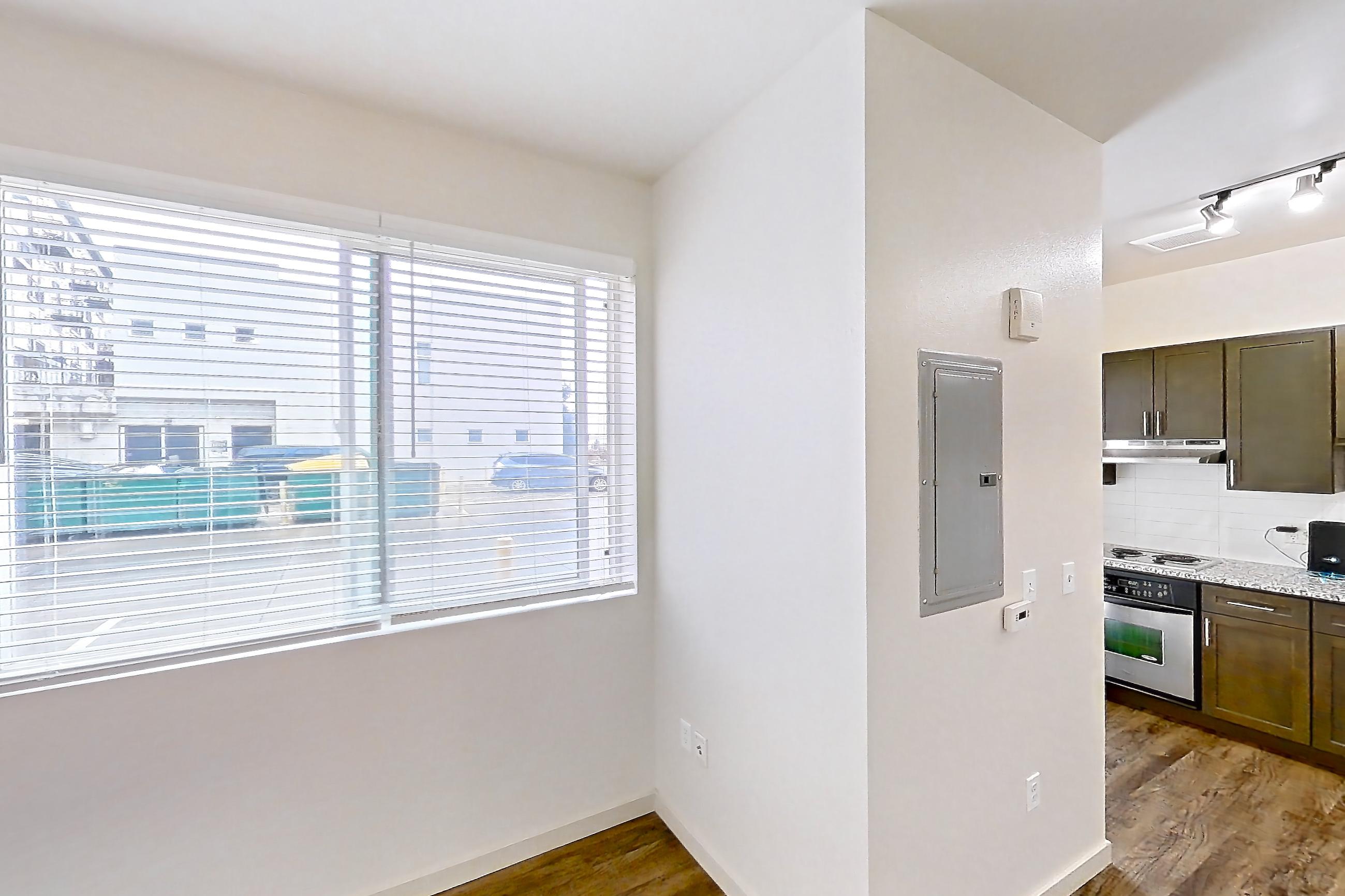 Living space with cooktop, dark wood-finish flooring, dishwasher, light stone countertops, oven/range, refrigerator, and stainless steel appliances, Apartment N102A at Cortland Alameda Station
