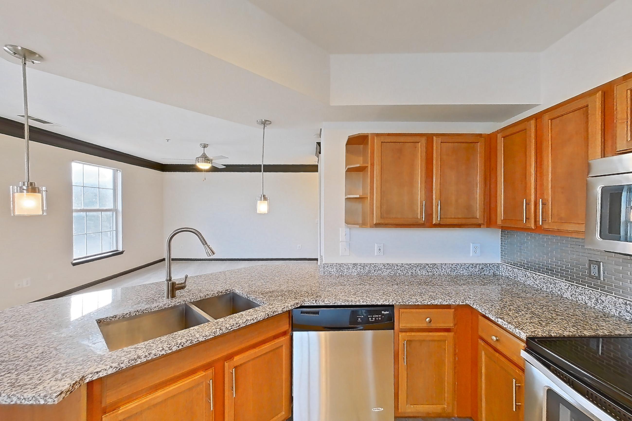 Kitchen with dishwasher, electric range, light carpet, light countertops, light stone countertops, light tile flooring, microwave, oven/range, refrigerator, and stainless steel appliances, Apartment 1-939 at Cortland Ridglea