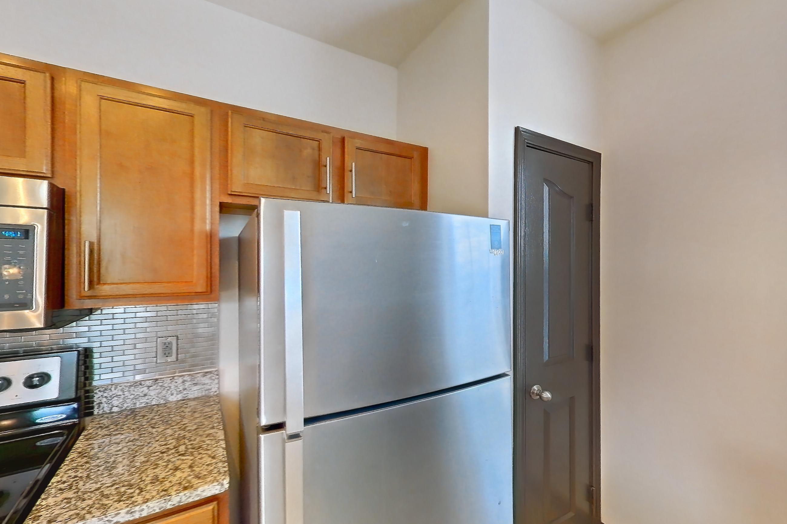 Kitchen with dishwasher, electric range, light carpet, light countertops, light stone countertops, light tile flooring, microwave, oven/range, refrigerator, and stainless steel appliances, Apartment 1-939 at Cortland Ridglea