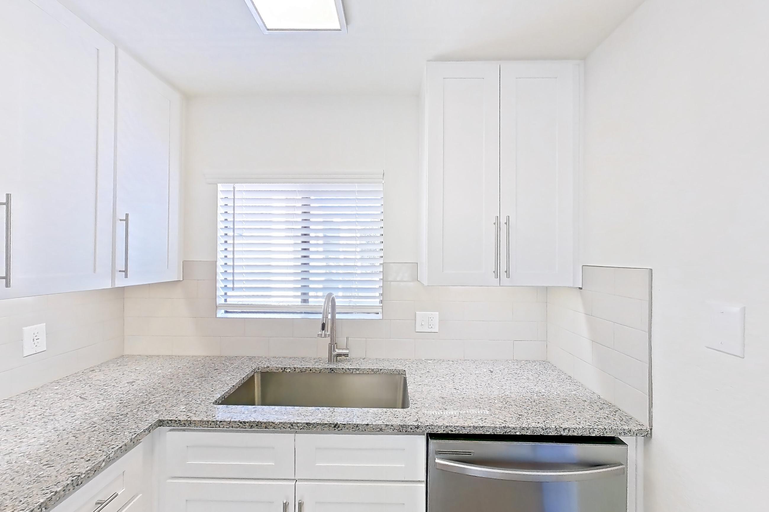 Kitchen with dishwasher, electric range, light countertops, light stone countertops, light wood-finish flooring, microwave, oven/range, range hood, refrigerator, and stainless steel appliances, Apartment 19289 at Cortland Sabino Canyon