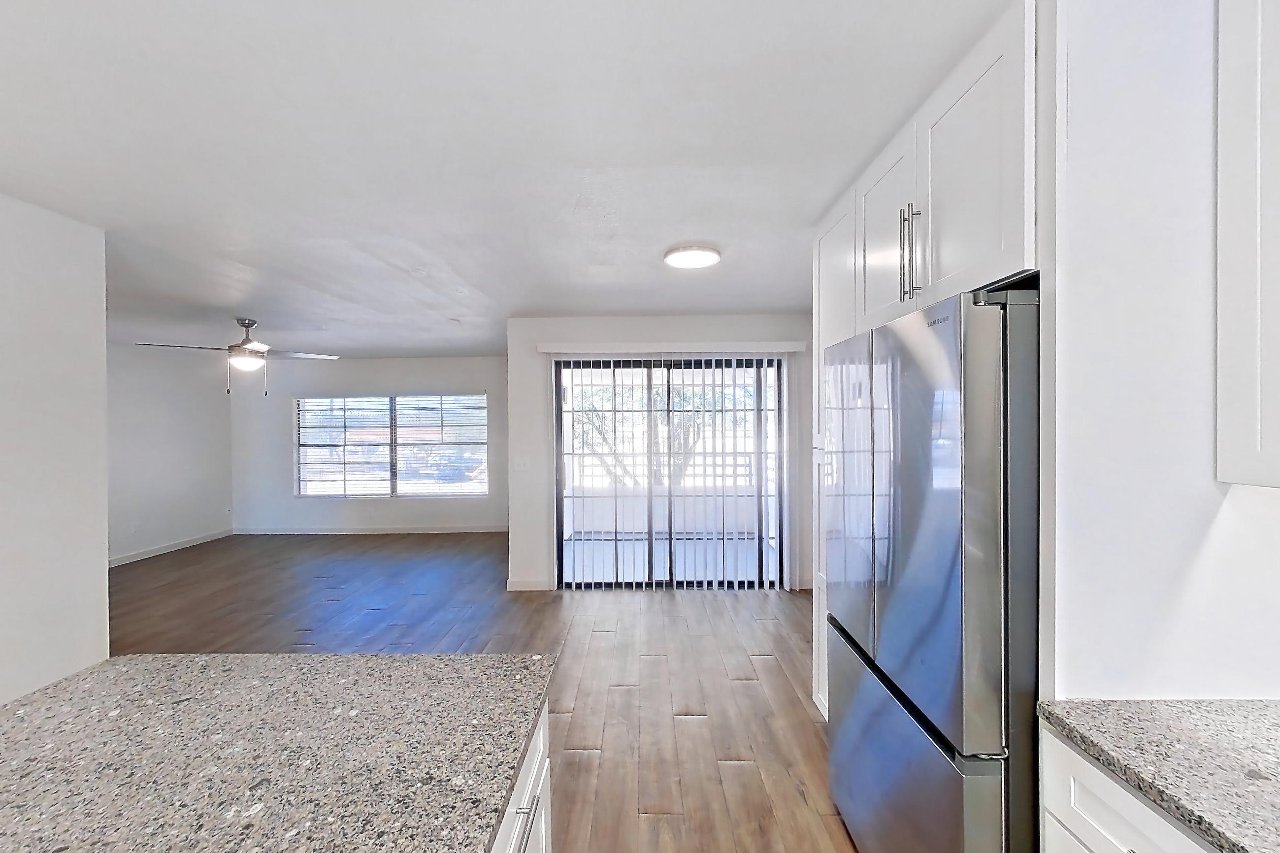 Kitchen with dishwasher, electric range, light countertops, light stone countertops, light wood-finish flooring, microwave, oven/range, range hood, refrigerator, and stainless steel appliances, Apartment 19289 at Cortland Sabino Canyon