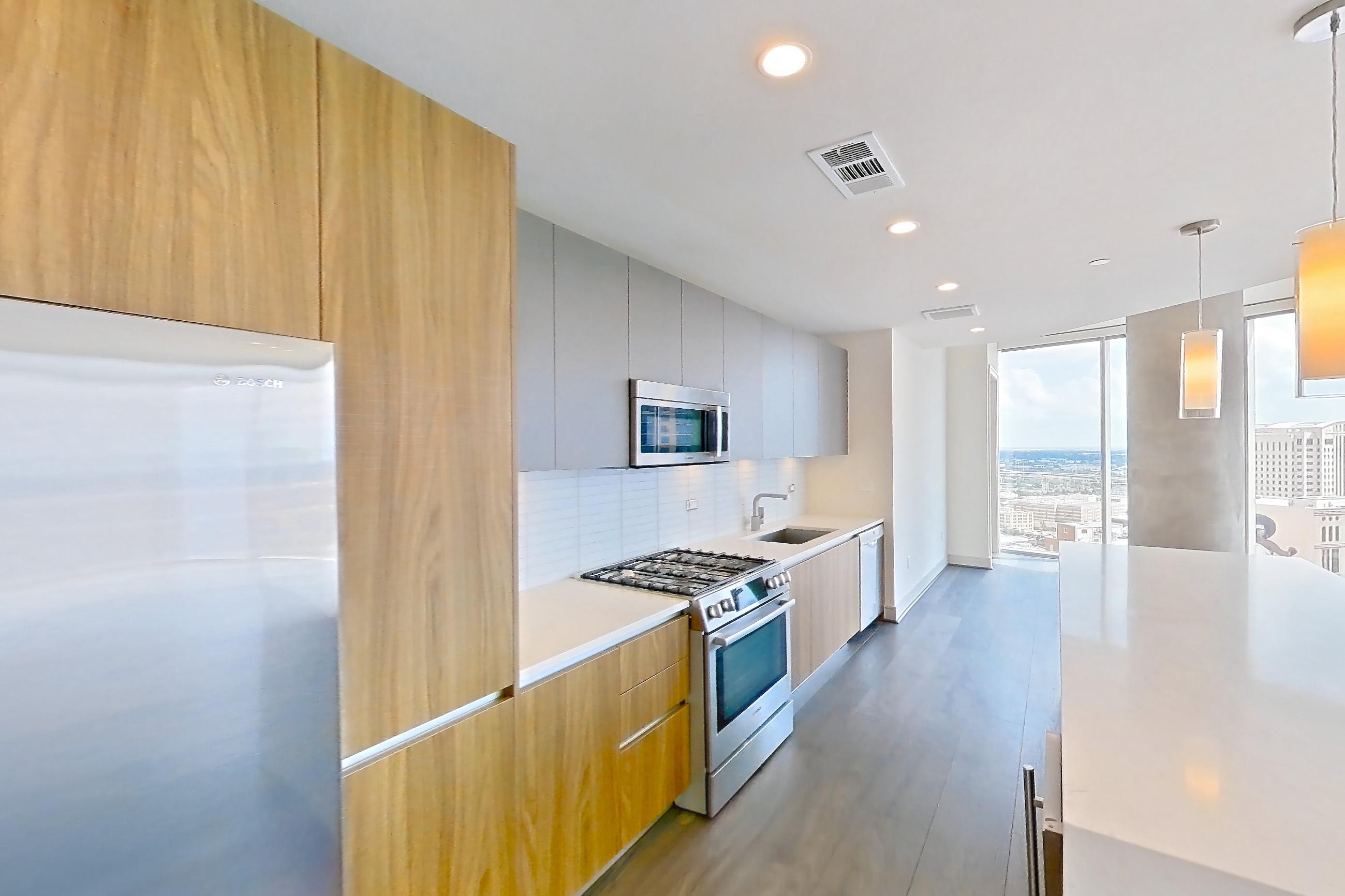 Kitchen space with dark wood-finish flooring, gas range, light countertops, oven/range, refrigerator, stainless steel appliances, and water & ice dispenser, Apartment 2803 at Brava