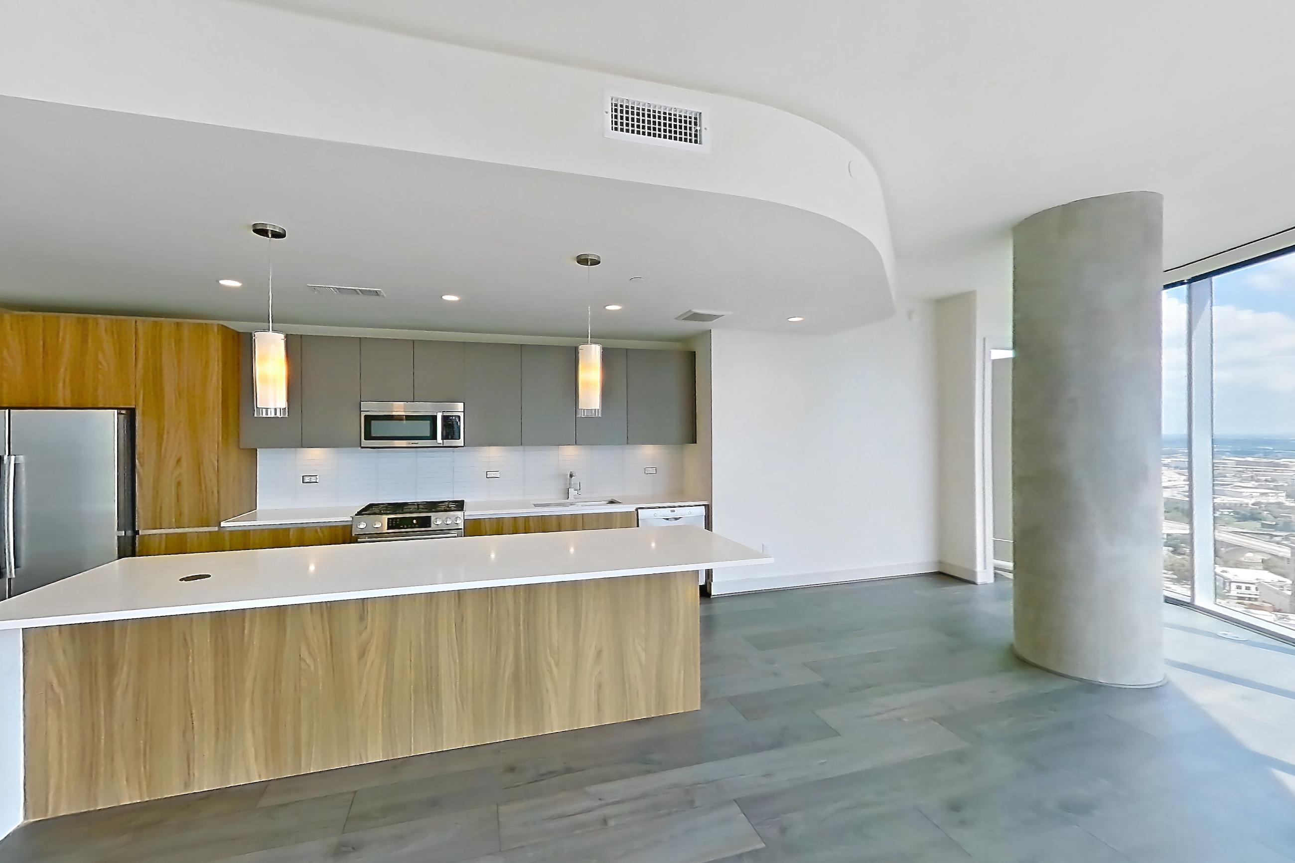 Living room with city view, dark wood-finish flooring, dishwasher, and white appliances, Apartment 2803 at Brava