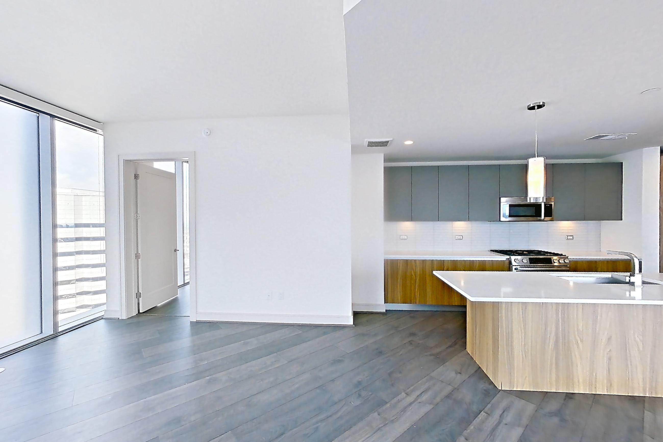 Living room with city view, dark wood-finish flooring, gas range, light stone countertops, oven/range, and stainless steel appliances, Apartment 3102 at Brava