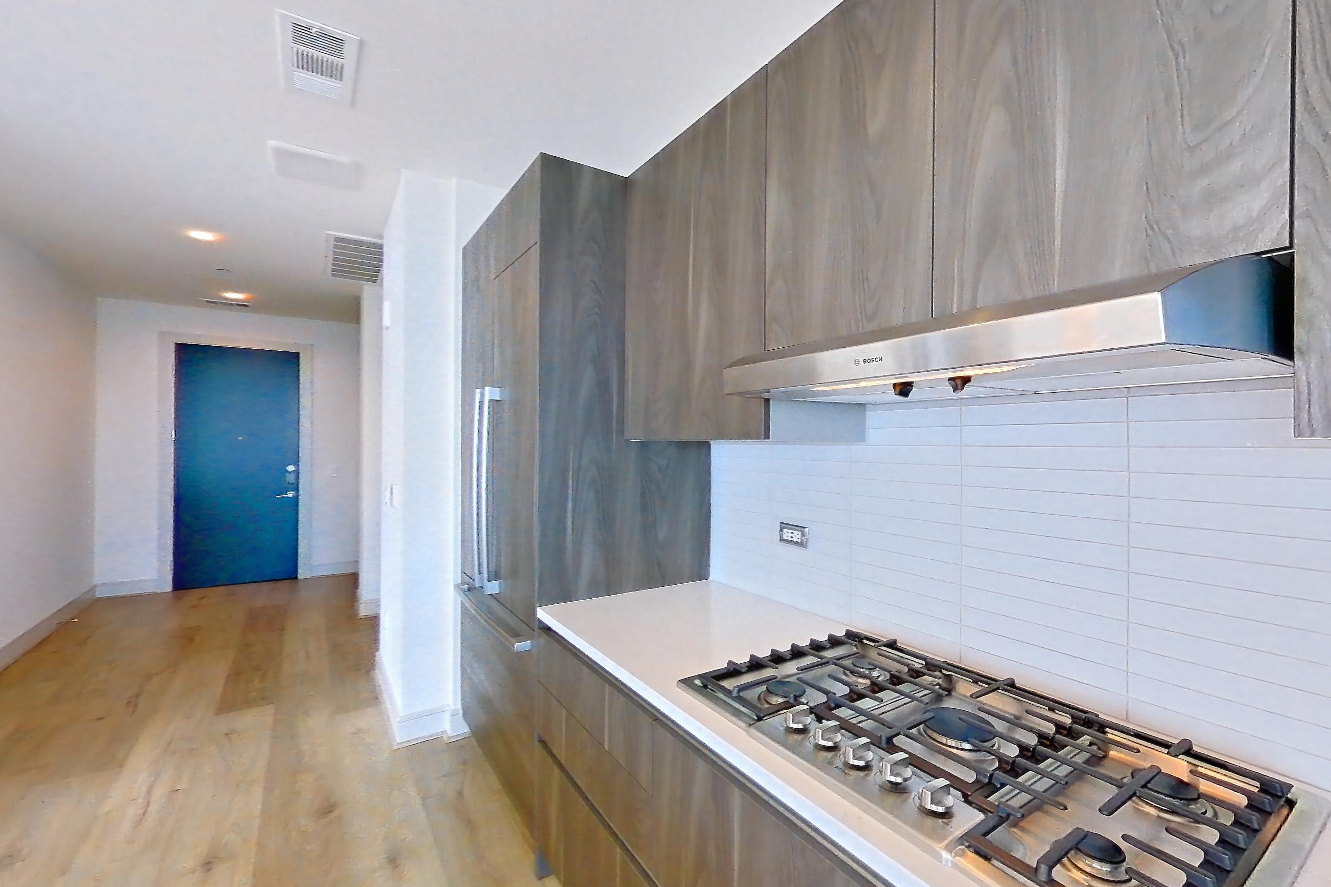 Kitchen with city view, cooktop, double oven, gas cooktop, light stone countertops, light wood-finish flooring, stainless steel appliances, and wood-finish flooring, Apartment 4602 at Brava