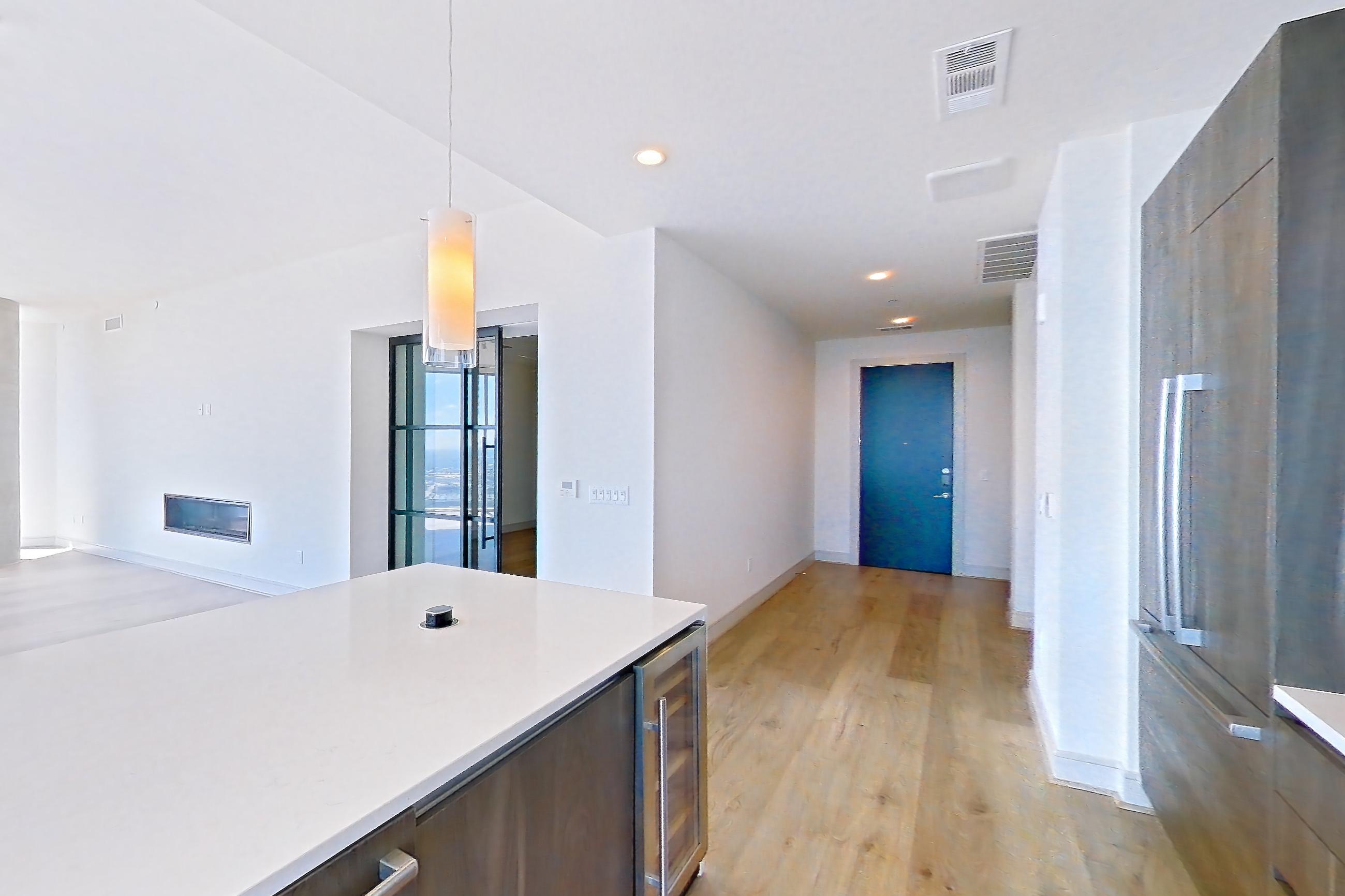 Kitchen with city view, cooktop, double oven, gas cooktop, light stone countertops, light wood-finish flooring, stainless steel appliances, and wood-finish flooring, Apartment 4602 at Brava