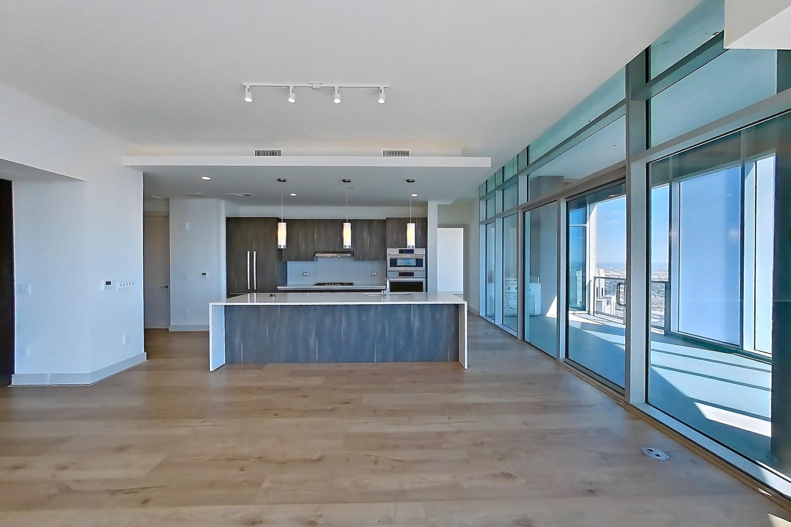Living room with dark wood-finish flooring, kitchen island, and light stone countertops, Apartment 4602 at Brava