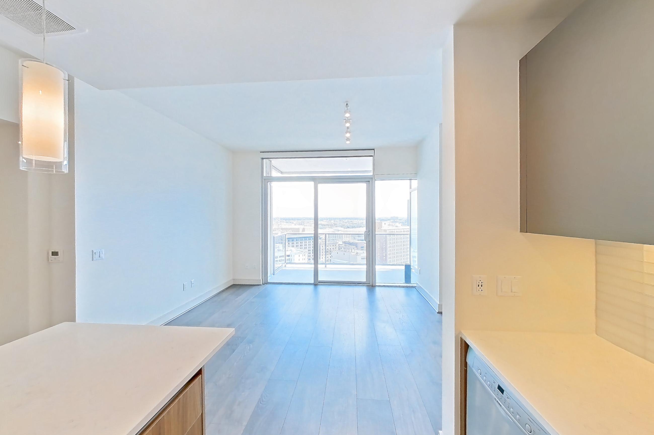 Kitchen with dark wood-finish flooring, dishwasher, gas range, light stone countertops, oven/range, stainless steel appliances, white appliances, and wood-finish flooring, Apartment 2006 at Brava