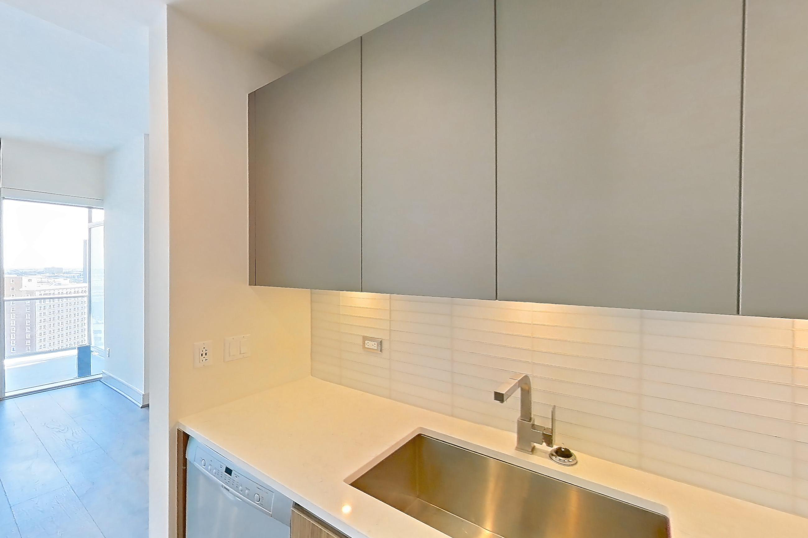 Kitchen with dark wood-finish flooring, dishwasher, gas range, light stone countertops, oven/range, stainless steel appliances, white appliances, and wood-finish flooring, Apartment 2006 at Brava