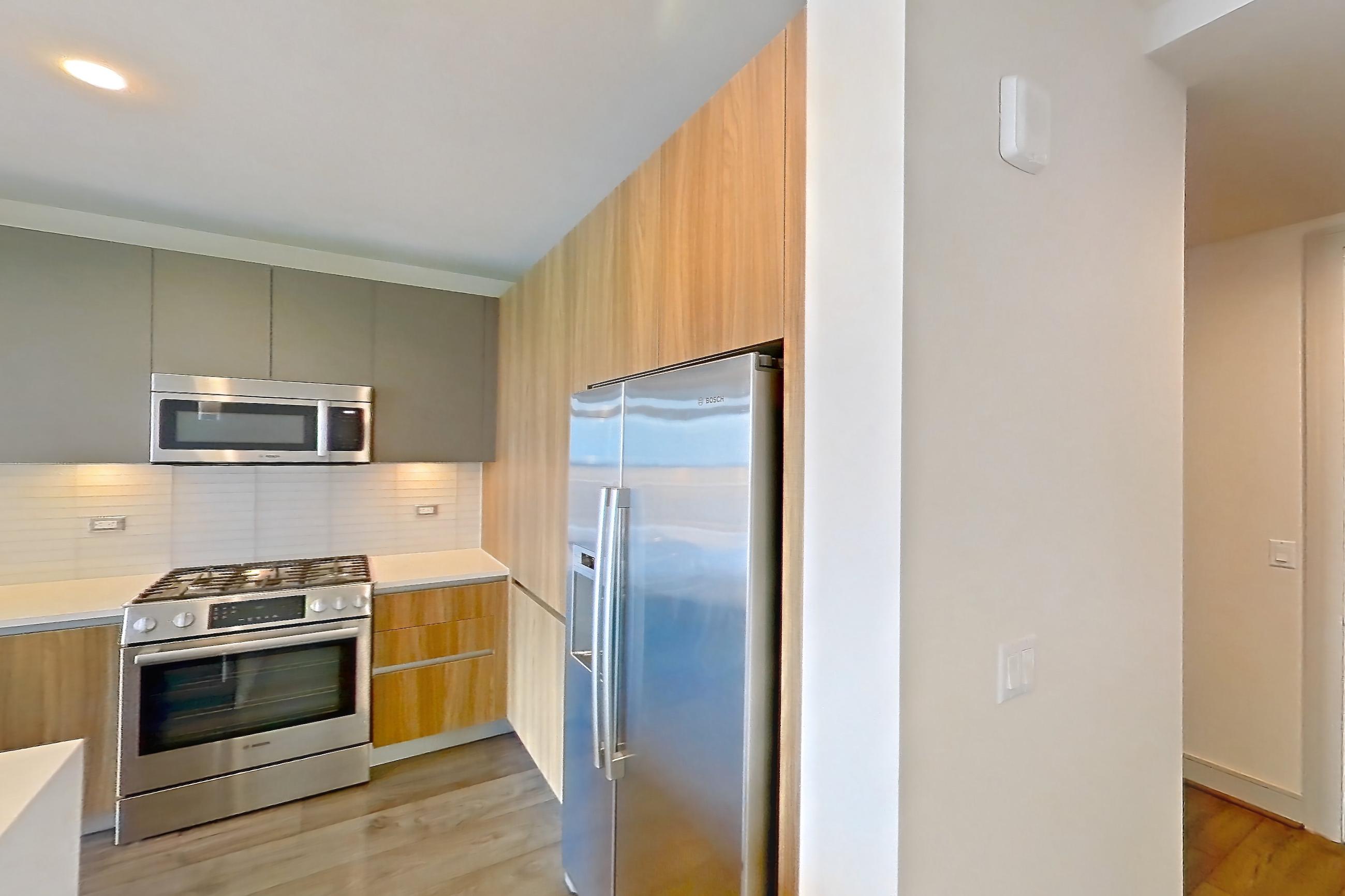 Living space with dark wood-finish flooring, dishwasher, gas range, light stone countertops, microwave, oven/range, refrigerator, stainless steel appliances, water & ice dispenser, white appliances, and wood-finish flooring, Apartment 2006 at Brava