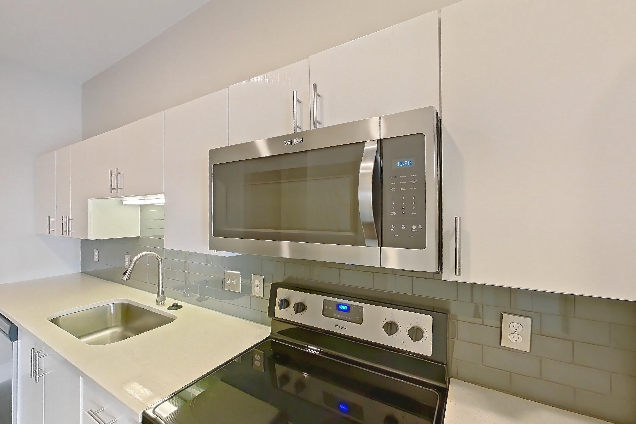 Kitchen with dark wood-finish flooring, electric range, light countertops, microwave, oven/range, and stainless steel appliances, Unit 279 at Harvest Lofts