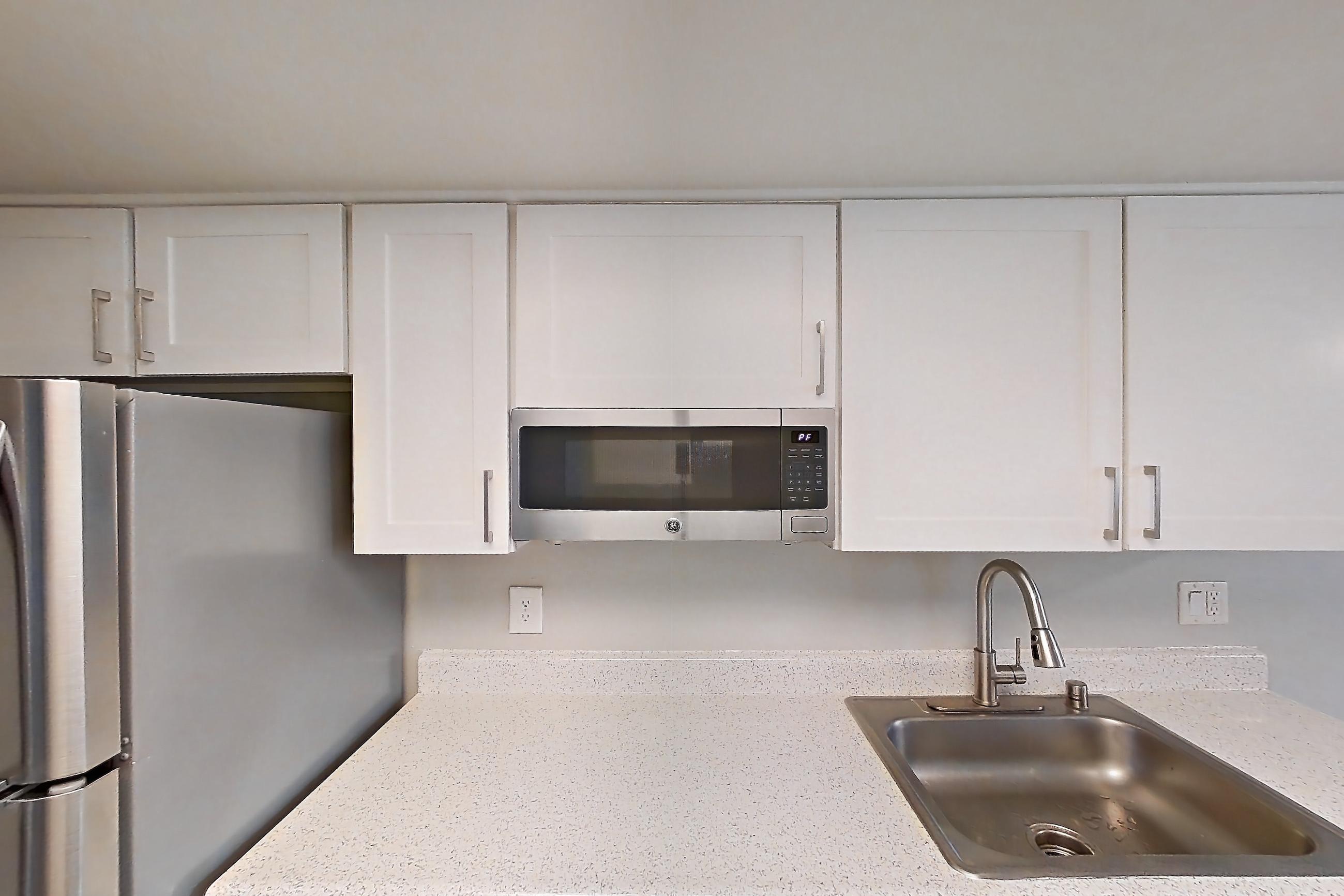 Kitchen with dishwasher, electric range, light stone countertops, light wood-finish flooring, oven/range, refrigerator, and stainless steel appliances, Apartment 07 at Avana Rancho Cucamonga