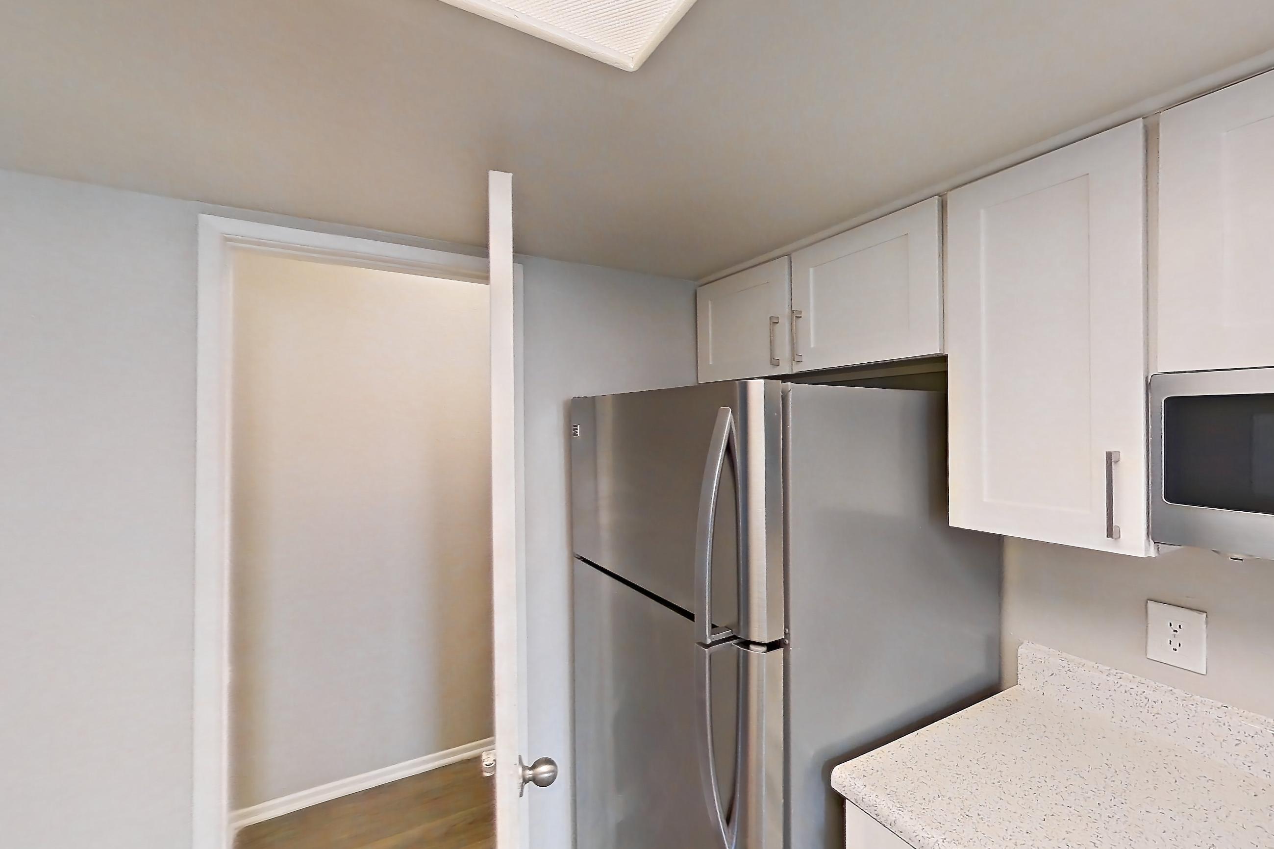 Kitchen with dishwasher, electric range, light stone countertops, light wood-finish flooring, oven/range, refrigerator, and stainless steel appliances, Apartment 07 at Avana Rancho Cucamonga