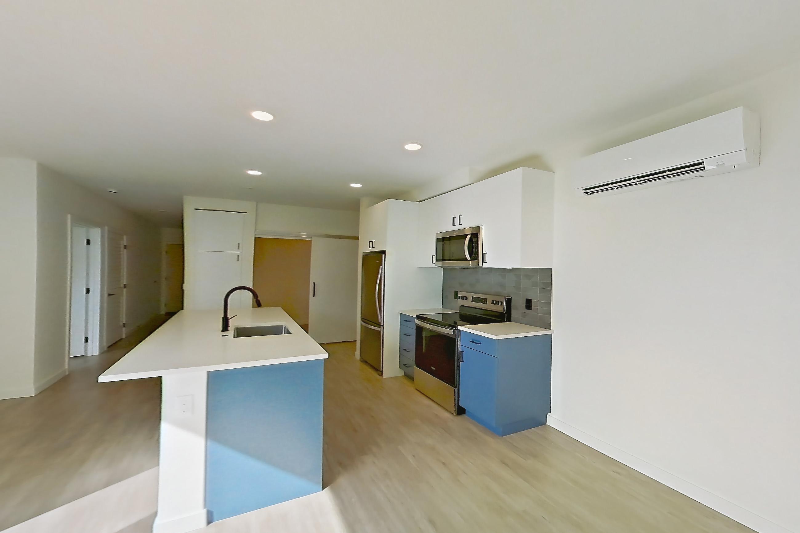 Living space with electric range, kitchen island, light countertops, light wood-finish flooring, microwave, oven/range, refrigerator, and stainless steel appliances, Apartment 743 at Cascara