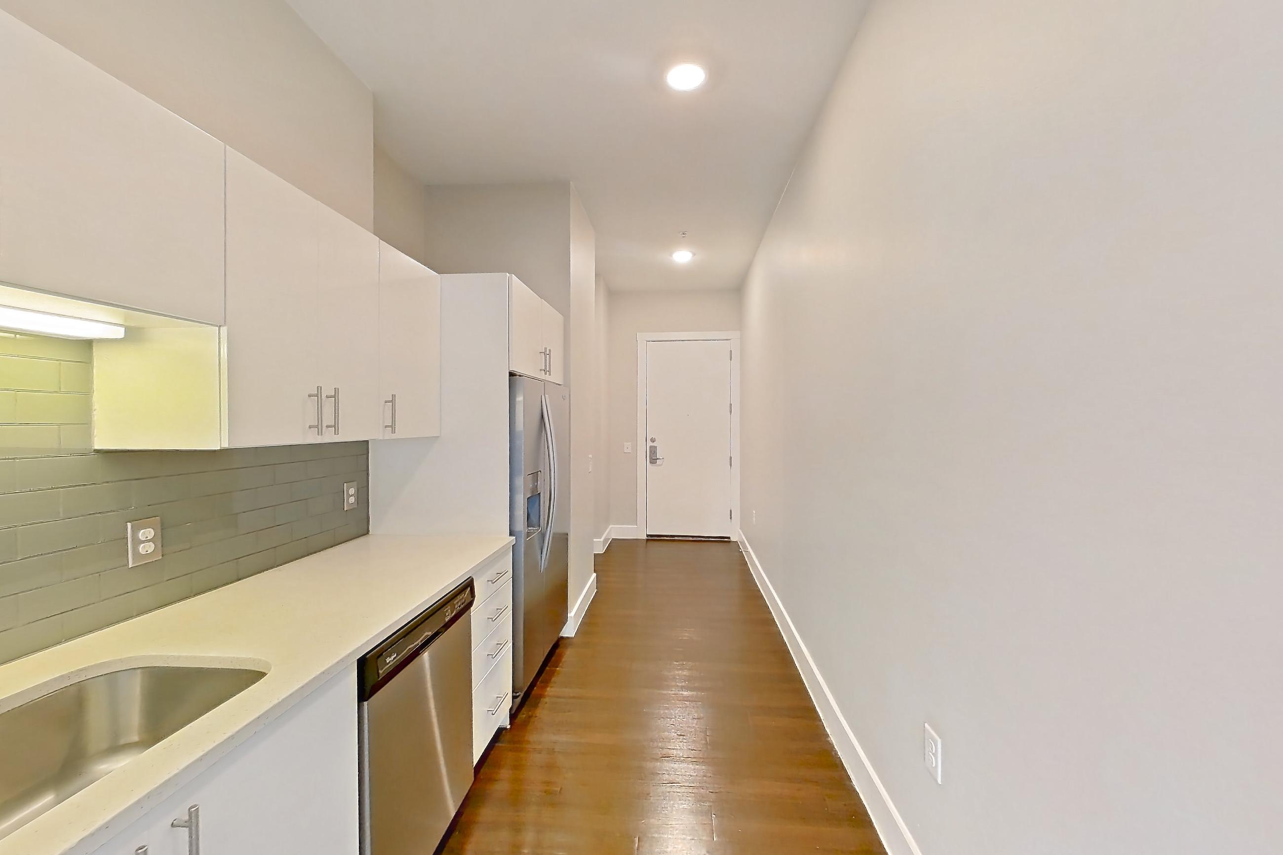 Kitchen with dark wood-finish flooring, dishwasher, electric range, light countertops, microwave, oven/range, stainless steel appliances, and wood-finish flooring, Unit 259 at Harvest Lofts