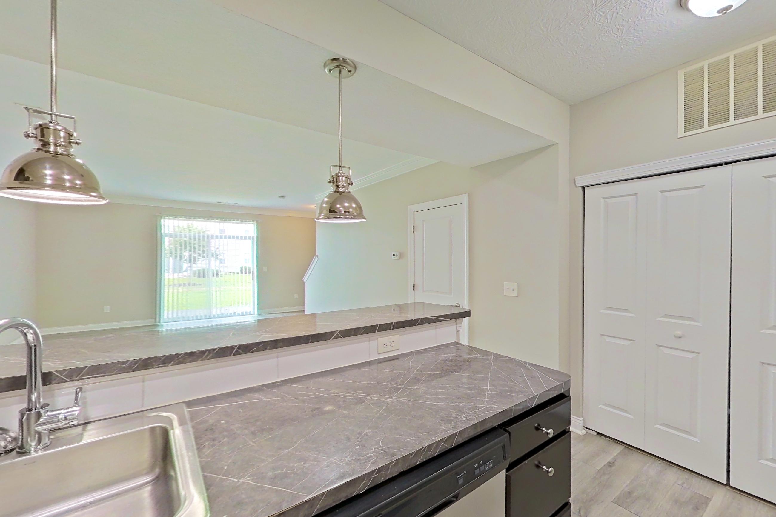 Kitchen with dark countertops, dishwasher, electric range, light countertops, light wood-finish flooring, microwave, oven/range, refrigerator, and stainless steel appliances, Apartment S9055 at Cortland Powell