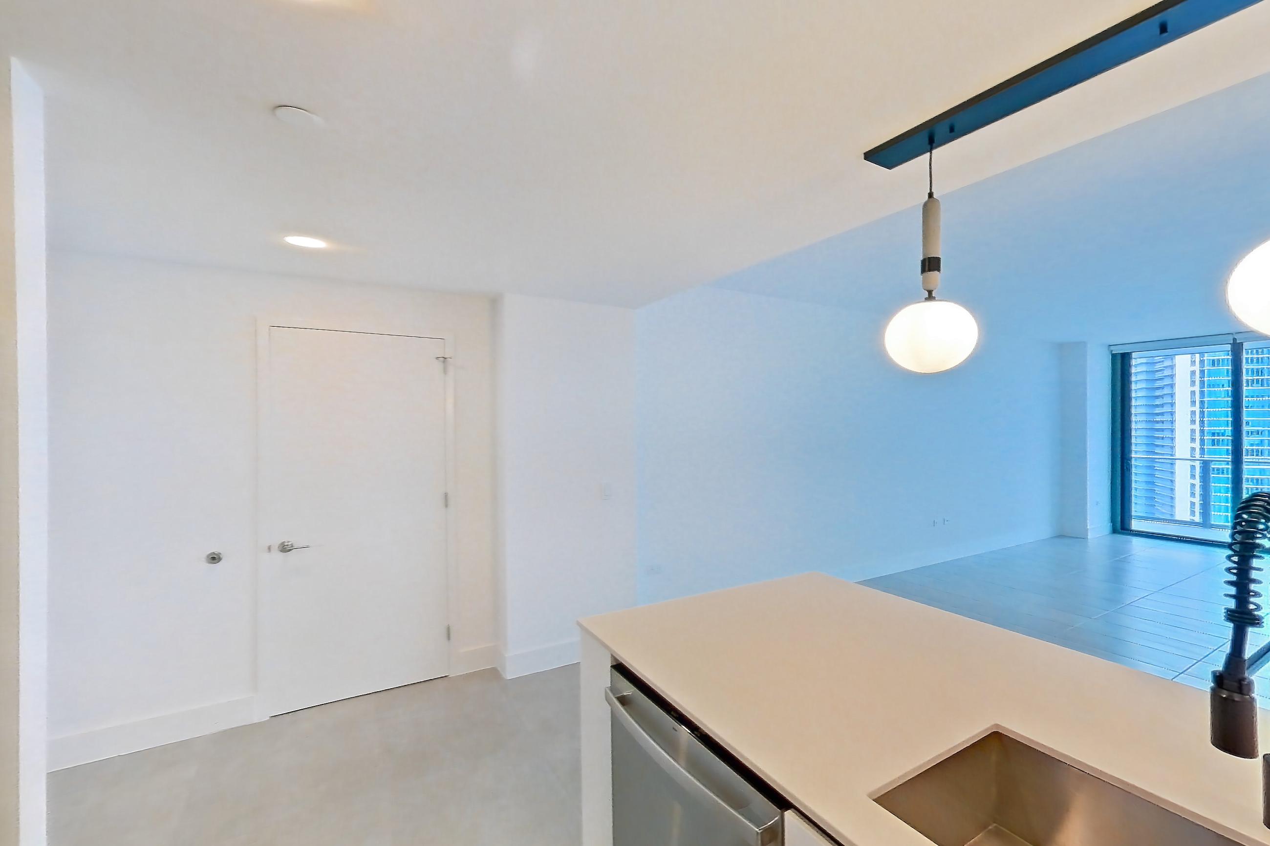 Kitchen with black appliances, cooktop, dishwasher, electric cooktop, light countertops, light tile flooring, oven/range, refrigerator, and stainless steel appliances, Apartment 4506 at Miami World Tower