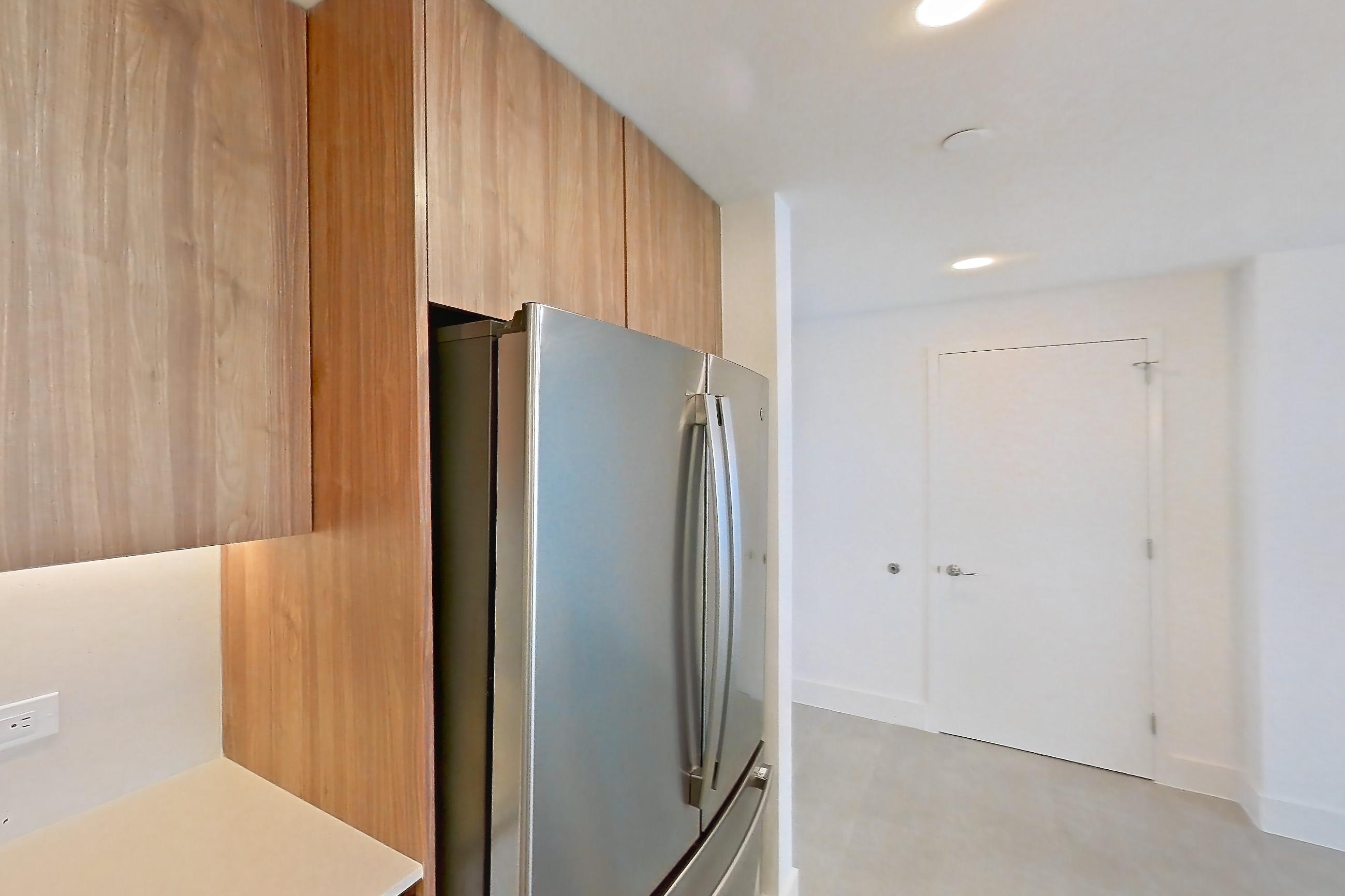 Kitchen with black appliances, cooktop, dishwasher, electric cooktop, light countertops, light tile flooring, oven/range, refrigerator, and stainless steel appliances, Apartment 4506 at Miami World Tower