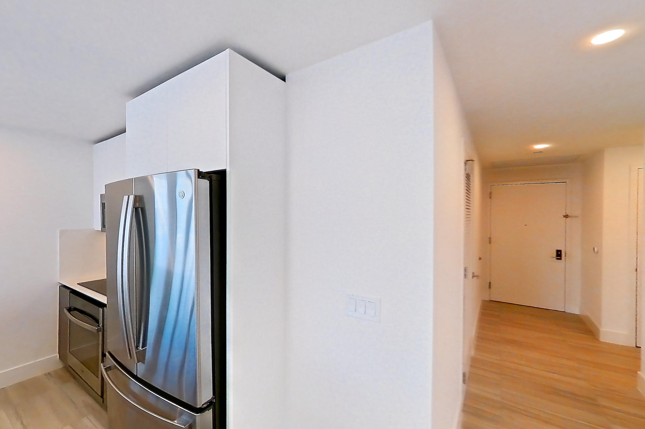 Kitchen entryway with dishwasher, light stone countertops, oven/range, refrigerator, and stainless steel appliances, Apartment 4601 at Miami World Tower