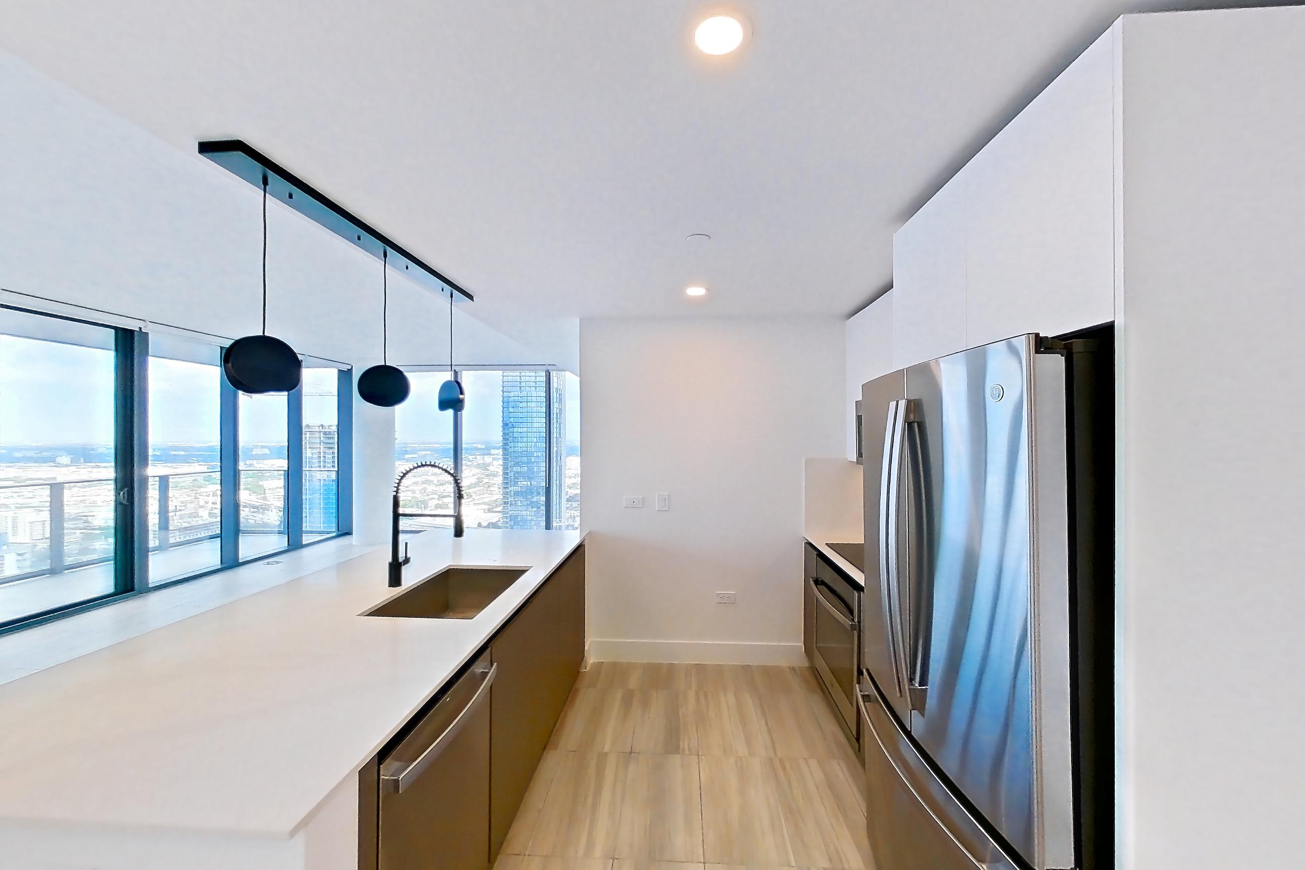 Kitchen entryway with dishwasher, light stone countertops, oven/range, refrigerator, and stainless steel appliances, Apartment 4601 at Miami World Tower