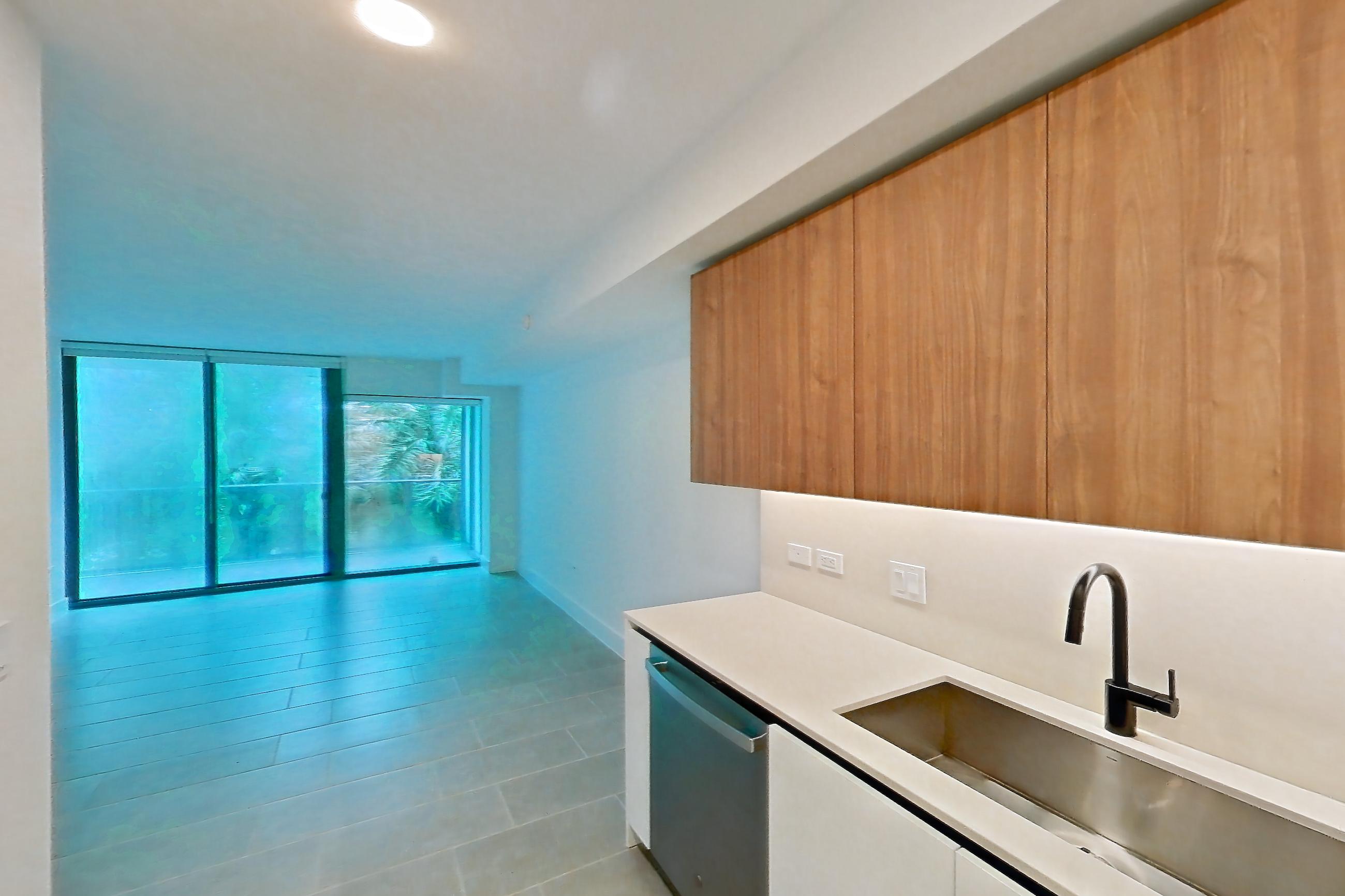 Kitchen with black appliances, cooktop, dishwasher, electric cooktop, light countertops, light tile flooring, oven/range, refrigerator, and stainless steel appliances, Apartment 0304 at Miami World Tower