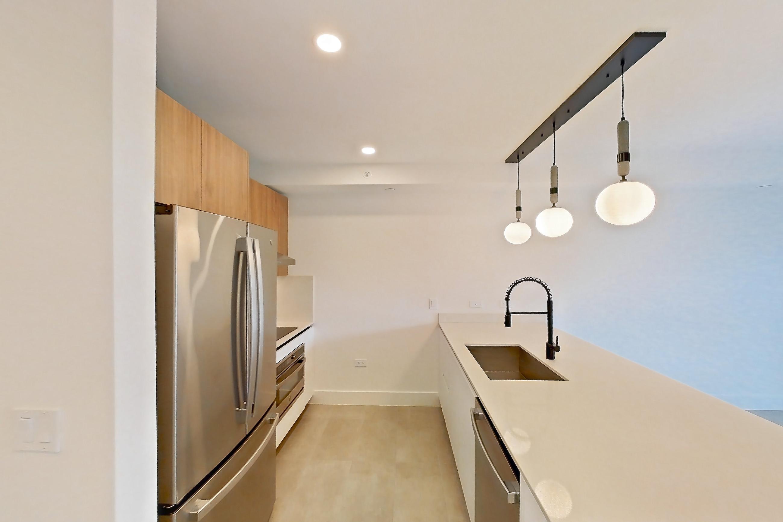 Kitchen entryway with dishwasher, light stone countertops, light tile flooring, oven/range, refrigerator, and stainless steel appliances, Apartment 0508 at Miami World Tower