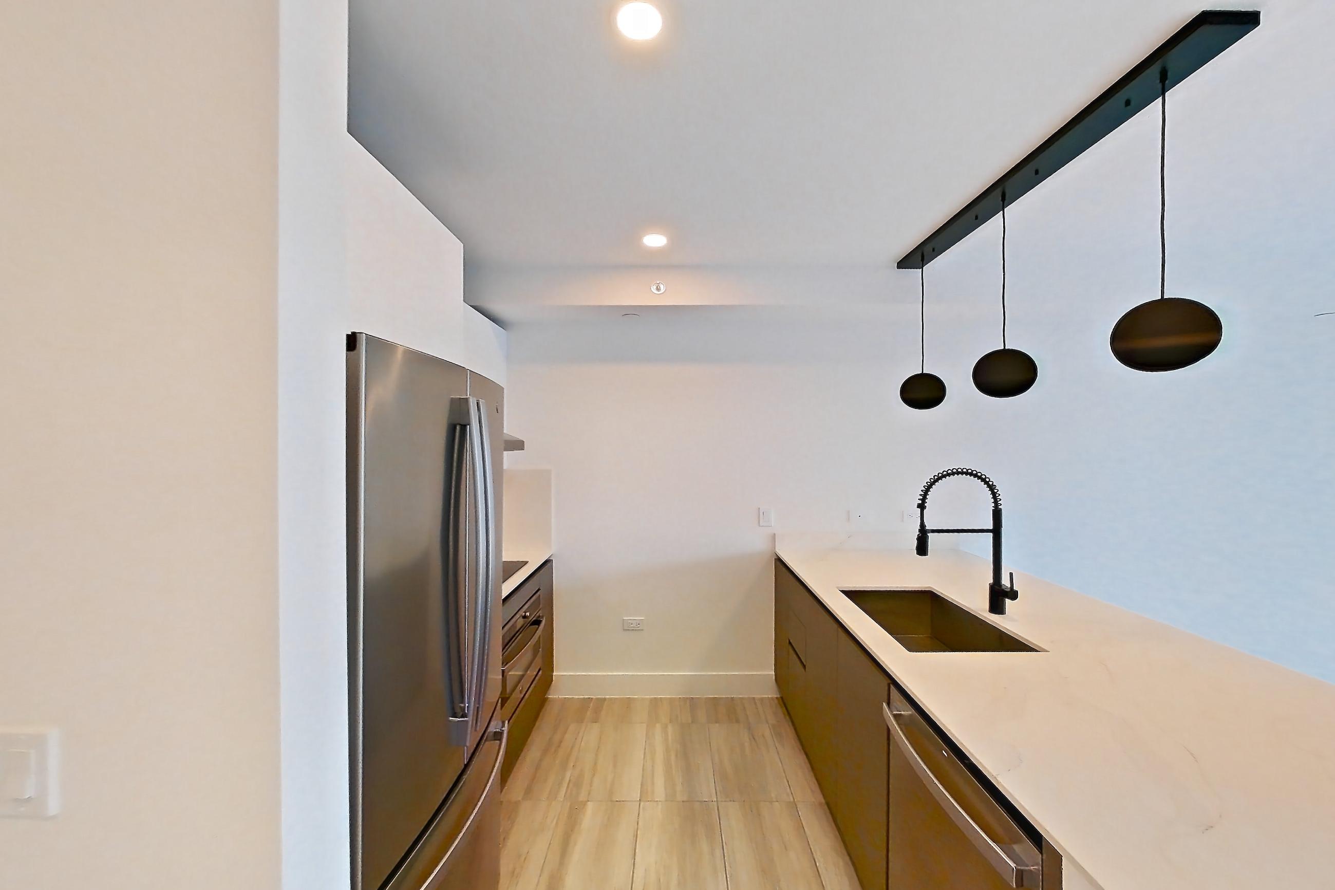 Kitchen entryway with dishwasher, light stone countertops, light tile flooring, refrigerator, and stainless steel appliances, Apartment 0608 at Miami World Tower