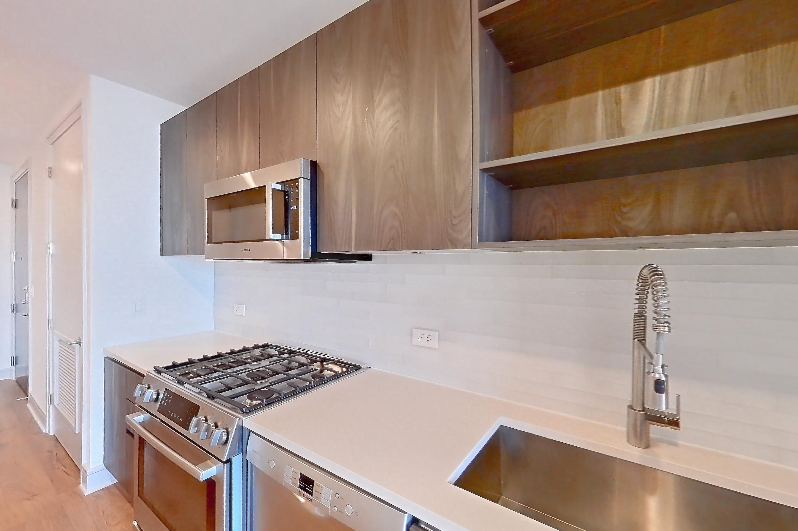 Kitchen with dishwasher, gas range, light countertops, light wood-finish flooring, oven/range, and stainless steel appliances, Apartment 2405 at The Residences at La Colombe d'Or
