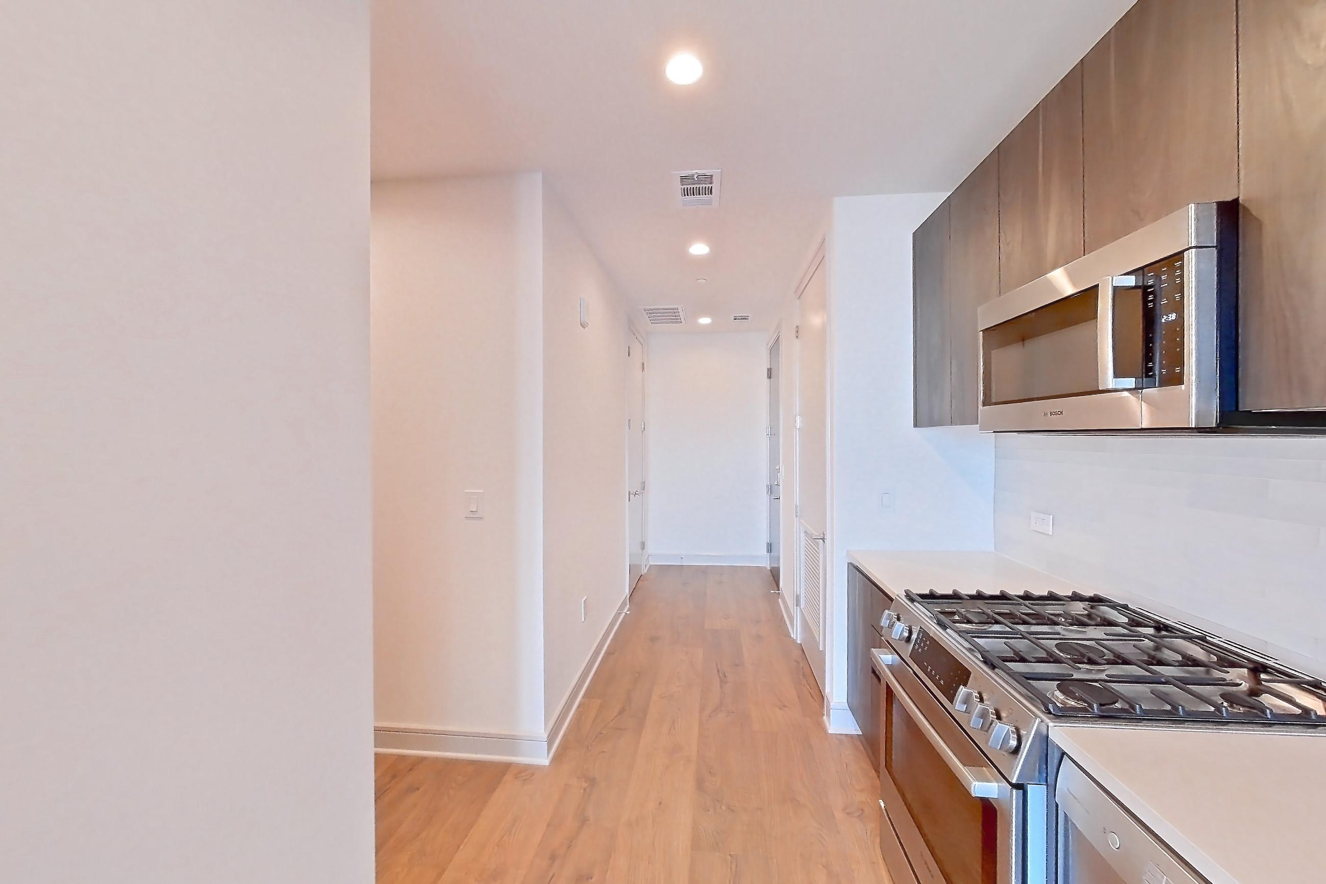Kitchen with dishwasher, gas range, light countertops, light wood-finish flooring, oven/range, and stainless steel appliances, Apartment 2405 at The Residences at La Colombe d'Or