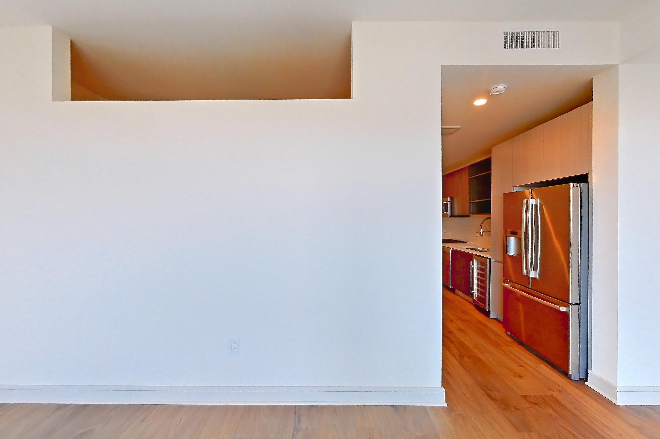 Living room with light wood-finish flooring and refrigerator, Apartment 2405 at The Residences at La Colombe d'Or