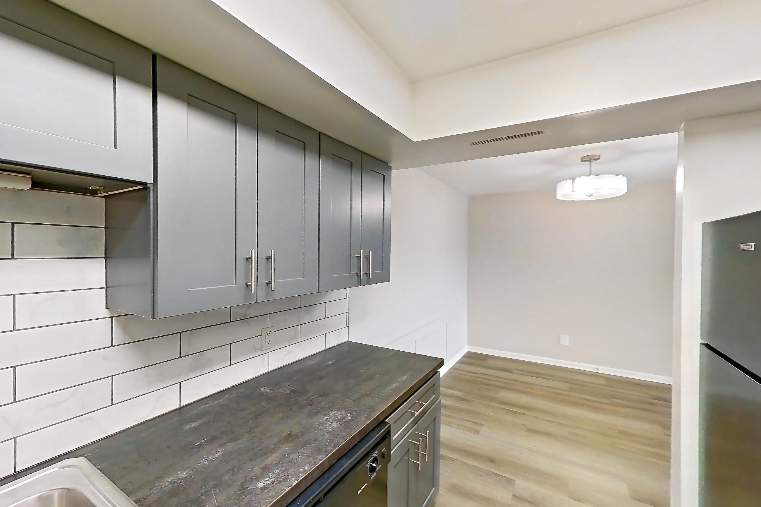 Kitchen with black appliances, dark stone countertops, dishwasher, electric range, light wood-finish flooring, oven/range, and refrigerator, Apartment 5160-9 at Canterbury Green