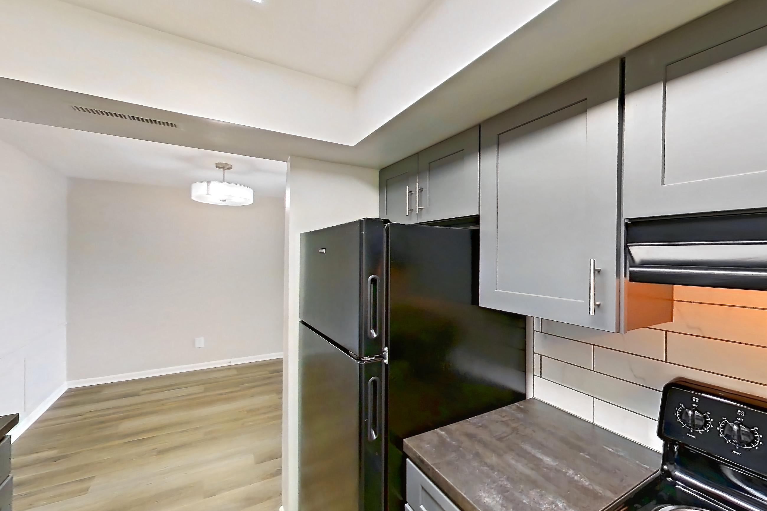 Kitchen with black appliances, dark stone countertops, dishwasher, electric range, light wood-finish flooring, oven/range, and refrigerator, Apartment 5160-9 at Canterbury Green
