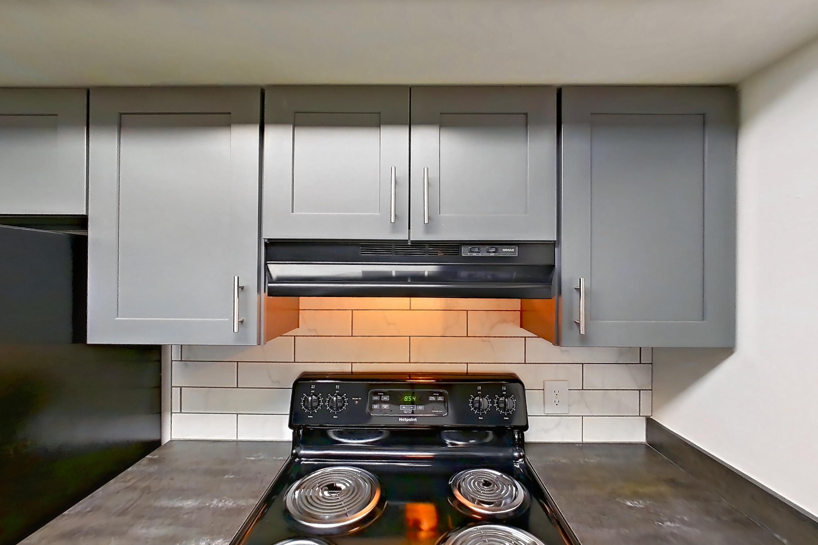 Kitchen with black appliances, dark stone countertops, dishwasher, electric range, light wood-finish flooring, oven/range, and refrigerator, Apartment 5160-9 at Canterbury Green
