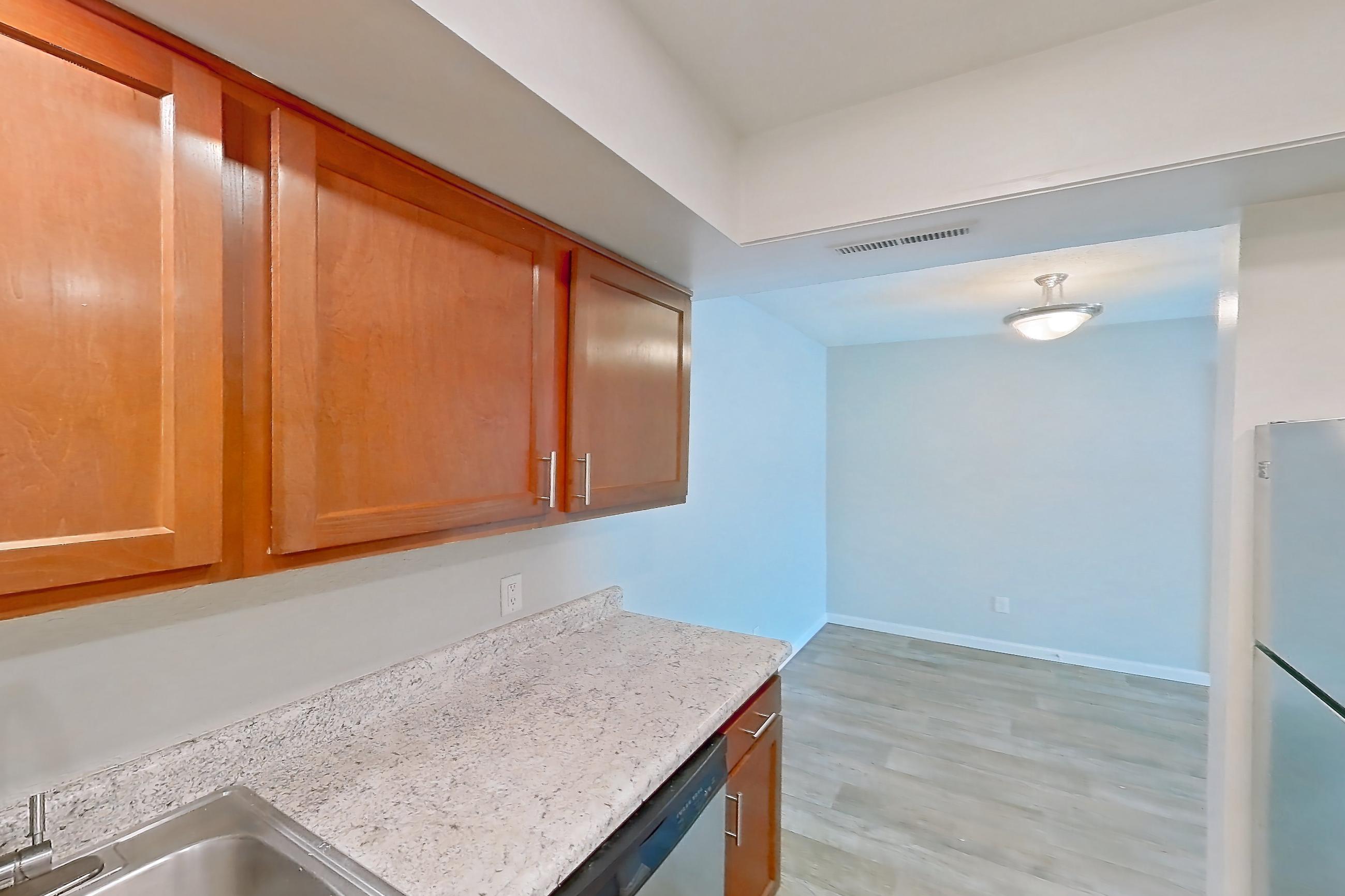 Kitchen with dishwasher, electric range, light stone countertops, light wood-finish flooring, oven/range, refrigerator, and stainless steel appliances, Apartment 5160-1 at Canterbury Green