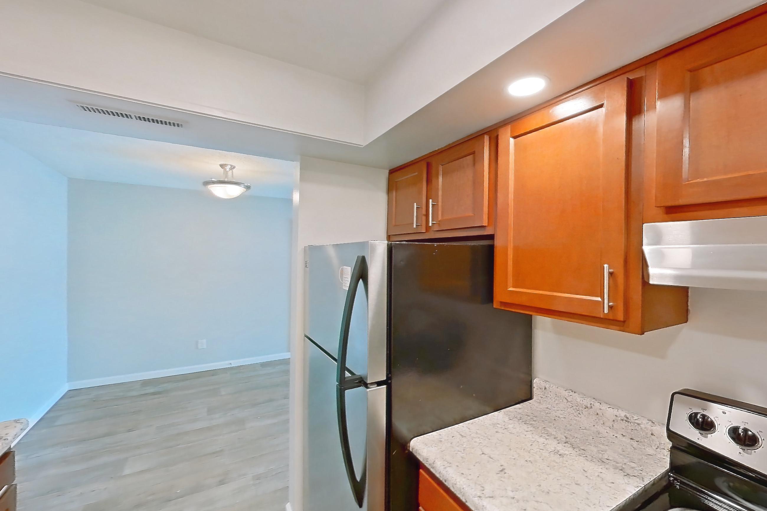 Kitchen with dishwasher, electric range, light stone countertops, light wood-finish flooring, oven/range, refrigerator, and stainless steel appliances, Apartment 5160-1 at Canterbury Green
