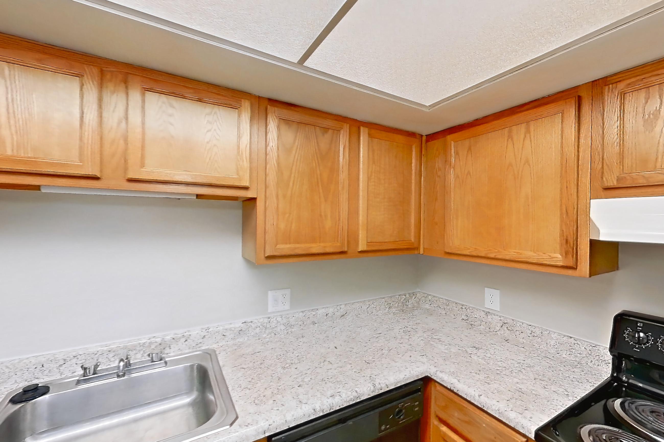 Kitchen with black appliances, dishwasher, electric range, light countertops, light stone countertops, light wood-finish flooring, and oven/range, Apartment 3007-4 at Canterbury Green