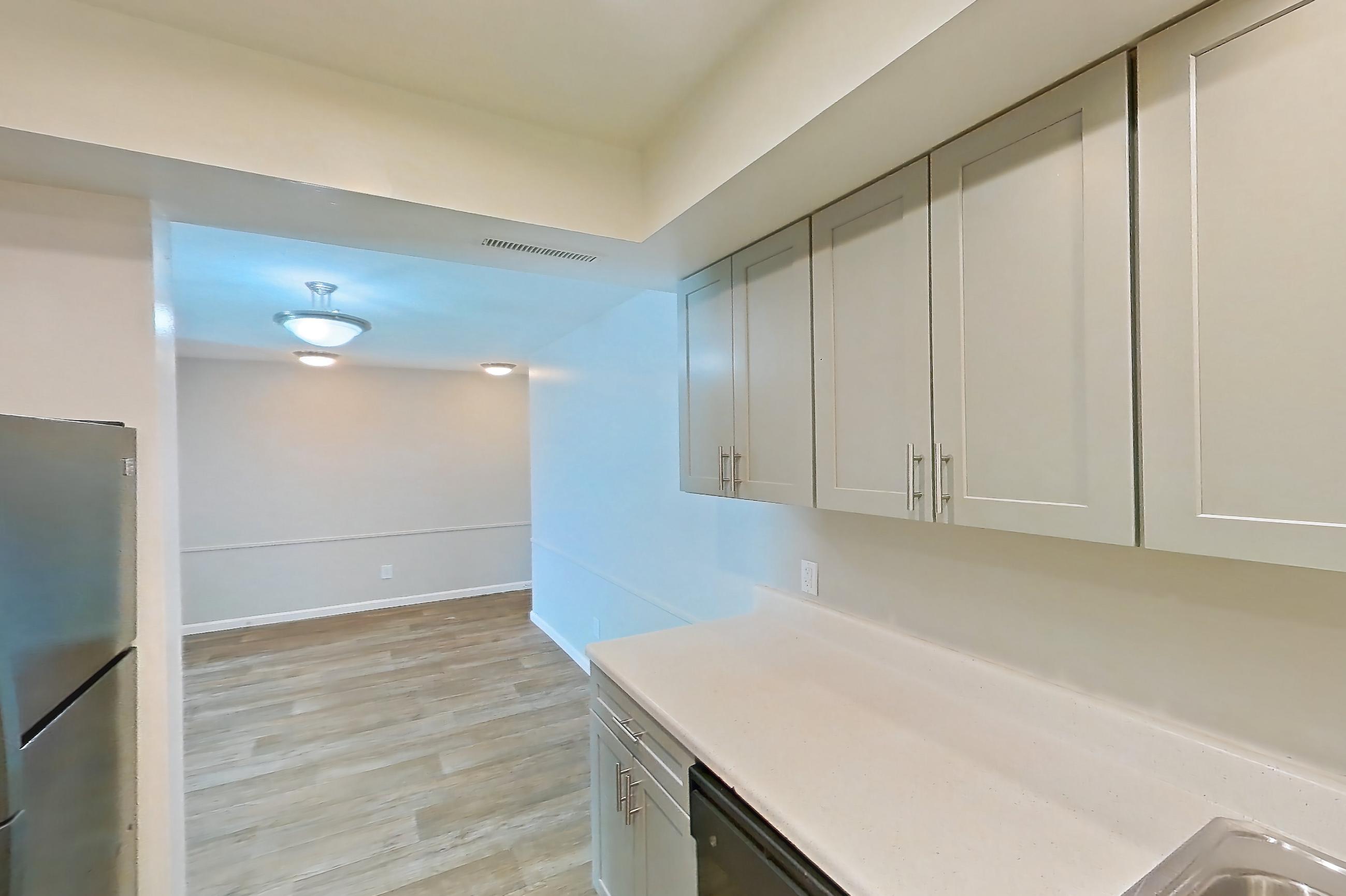 Kitchen with black appliances, dishwasher, electric range, light countertops, light wood-finish flooring, oven/range, refrigerator, and stainless steel appliances, Apartment 5201-2 at Canterbury Green