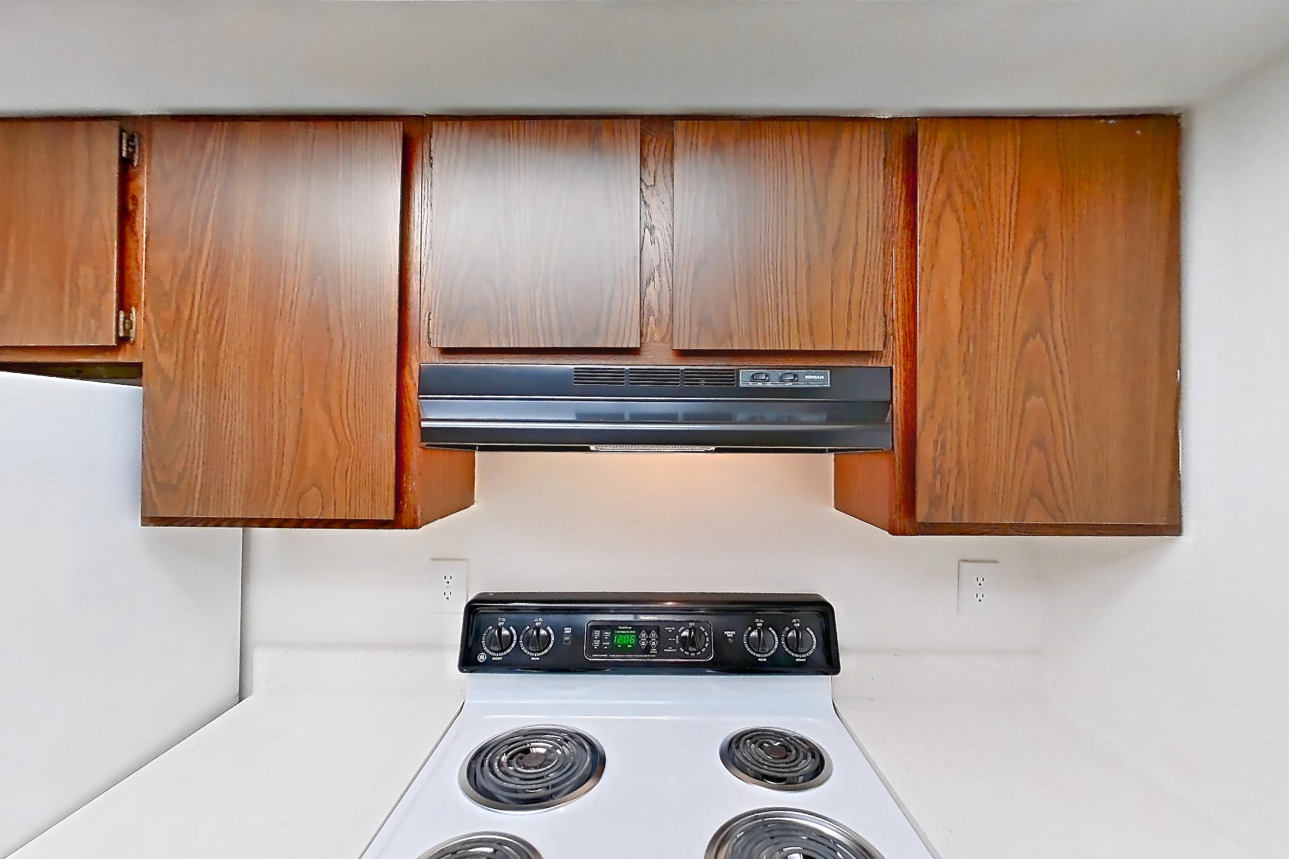 Kitchen with black appliances, dishwasher, electric range, light carpet, light countertops, light wood-finish flooring, oven/range, refrigerator, and white appliances, Apartment 5612-2ST at Canterbury Green