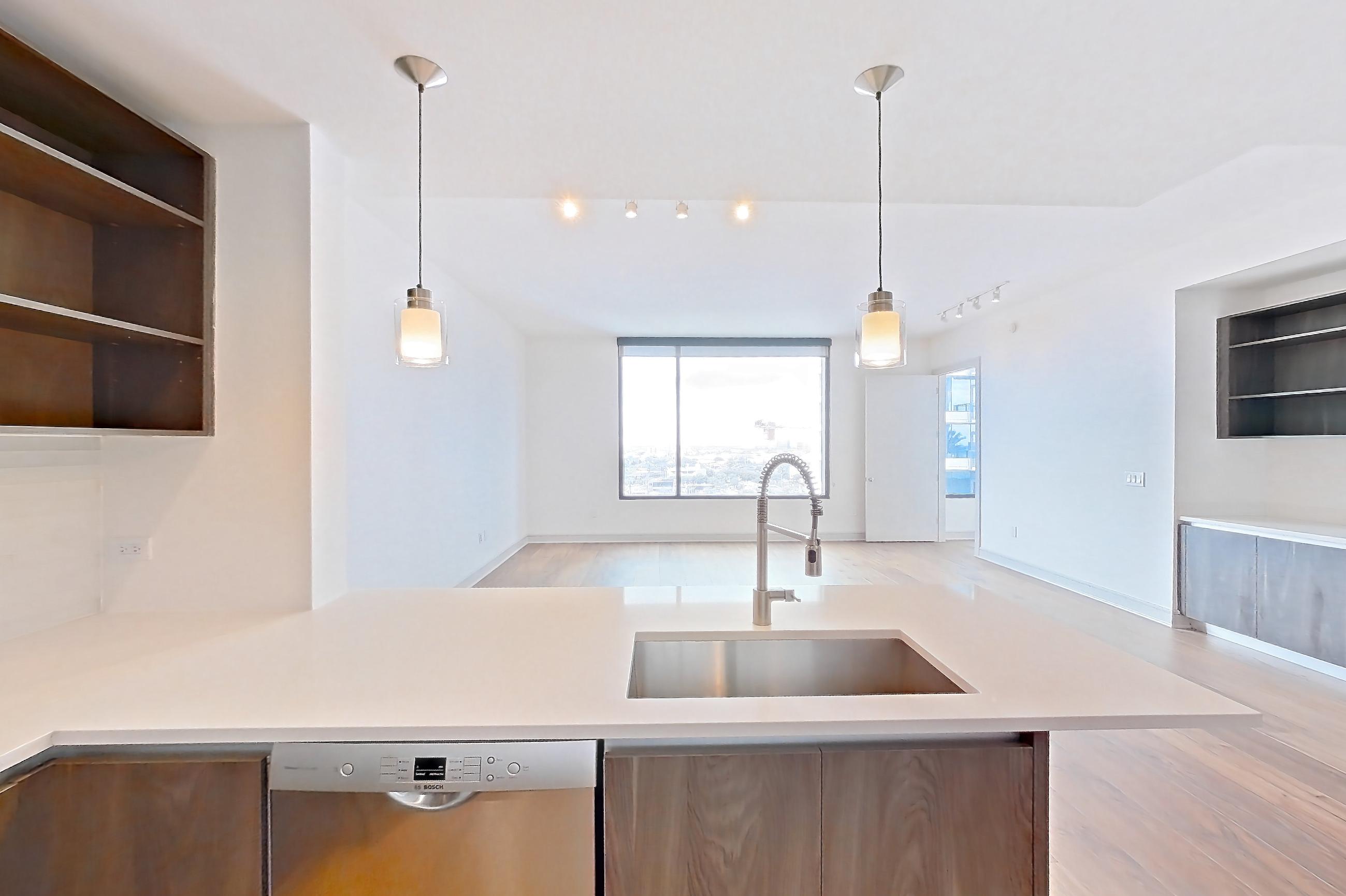 Kitchen with dishwasher, gas range, light countertops, light stone countertops, light wood-finish flooring, microwave, oven/range, stainless steel appliances, and wood-finish flooring, Apartment 1102 at The Residences at La Colombe d'Or