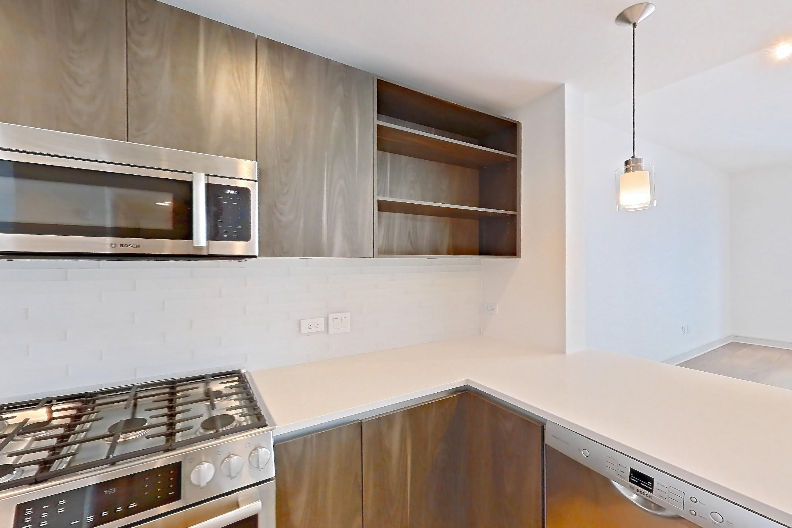 Kitchen with dishwasher, gas range, light countertops, light stone countertops, light wood-finish flooring, microwave, oven/range, stainless steel appliances, and wood-finish flooring, Apartment 1102 at The Residences at La Colombe d'Or