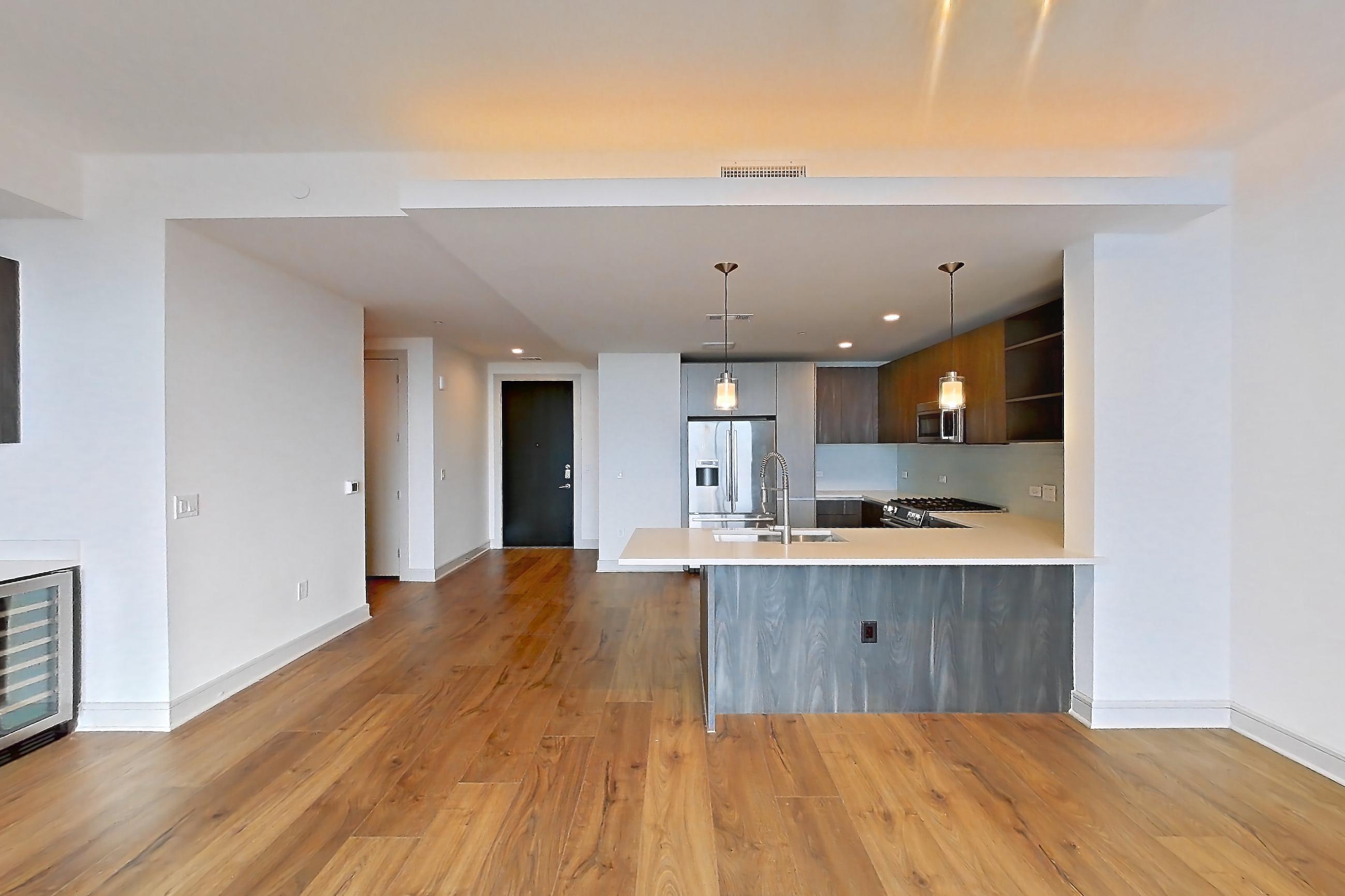 Living room with gas range, light countertops, light wood-finish flooring, oven/range, parquet flooring, refrigerator, and stainless steel appliances, Apartment 1102 at The Residences at La Colombe d'Or