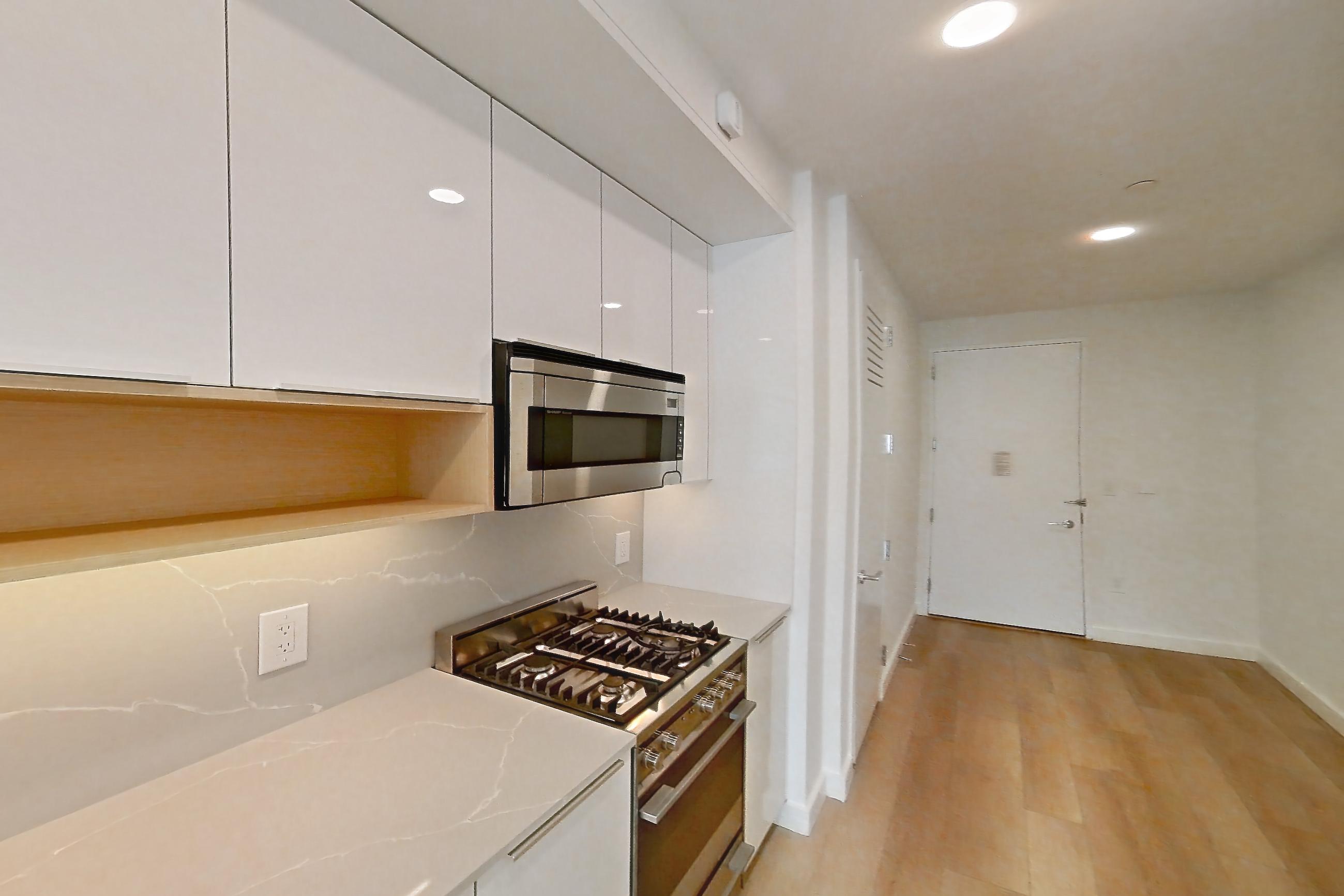 Kitchen with gas range, light stone countertops, light wood-finish flooring, oven/range, and stainless steel appliances, Apartment 2406 at 20 Broad