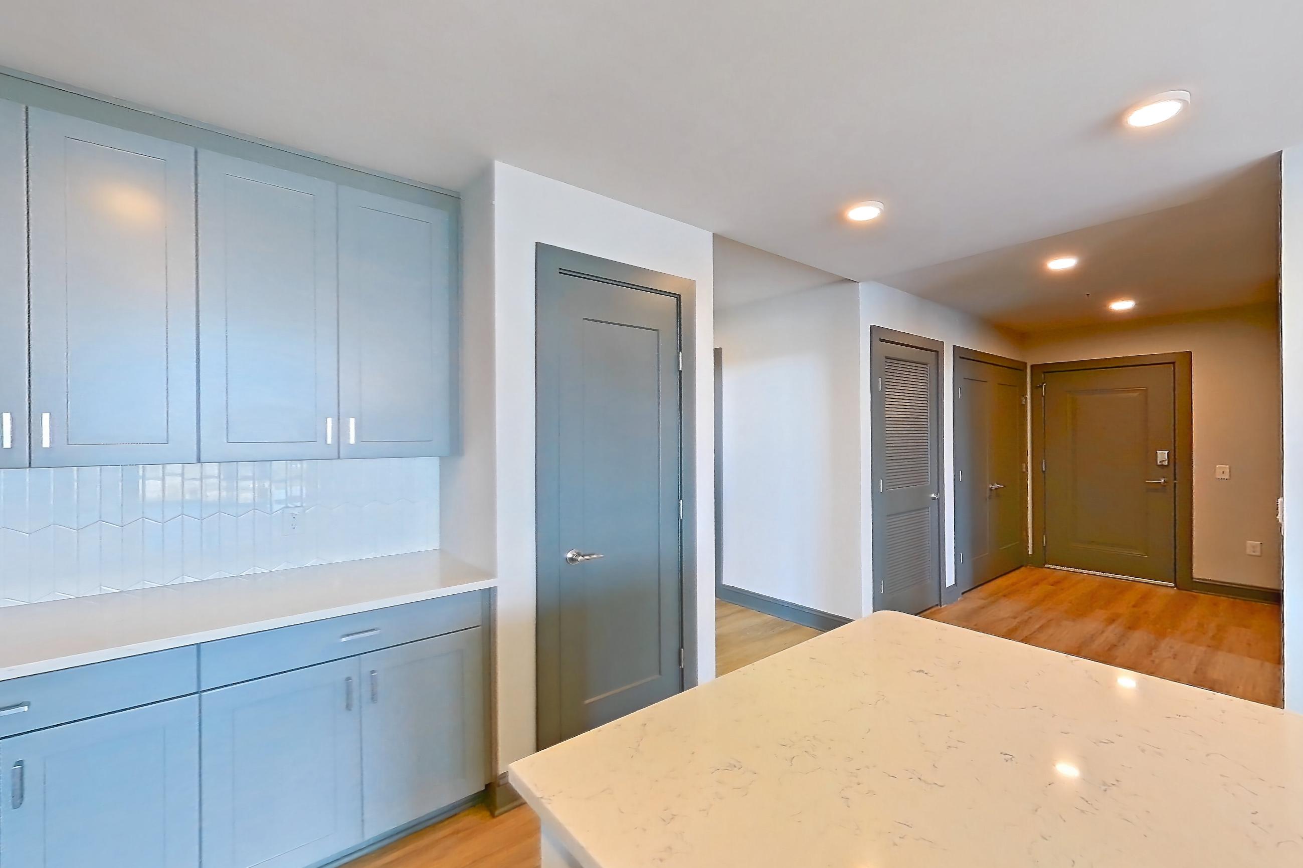Kitchen with dishwasher, electric range, light countertops, light stone countertops, light wood-finish flooring, microwave, oven/range, refrigerator, stainless steel appliances, water & ice dispenser, and white appliances, Apartment 1032 at Cortland Glenwood South